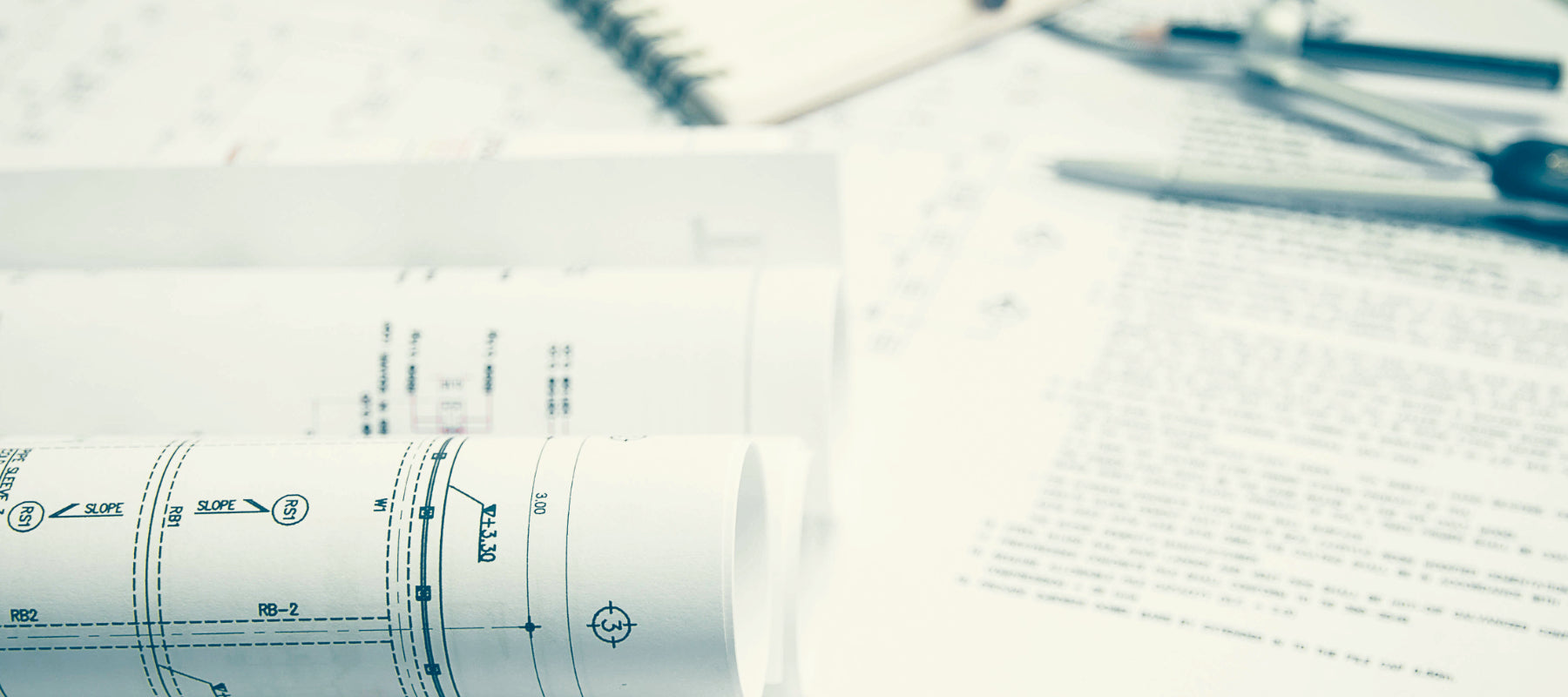 Schreibtisch mit Bauplänen, Ausschreibungstexten, Zirkle, Bleistift und Notizheft