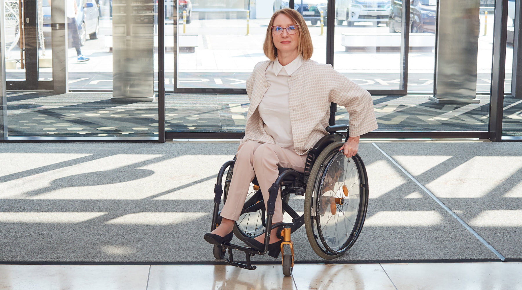 Eingangsbereich mit Fußmatten vor denen eine Rollstuhlfahrerin zu sehen ist