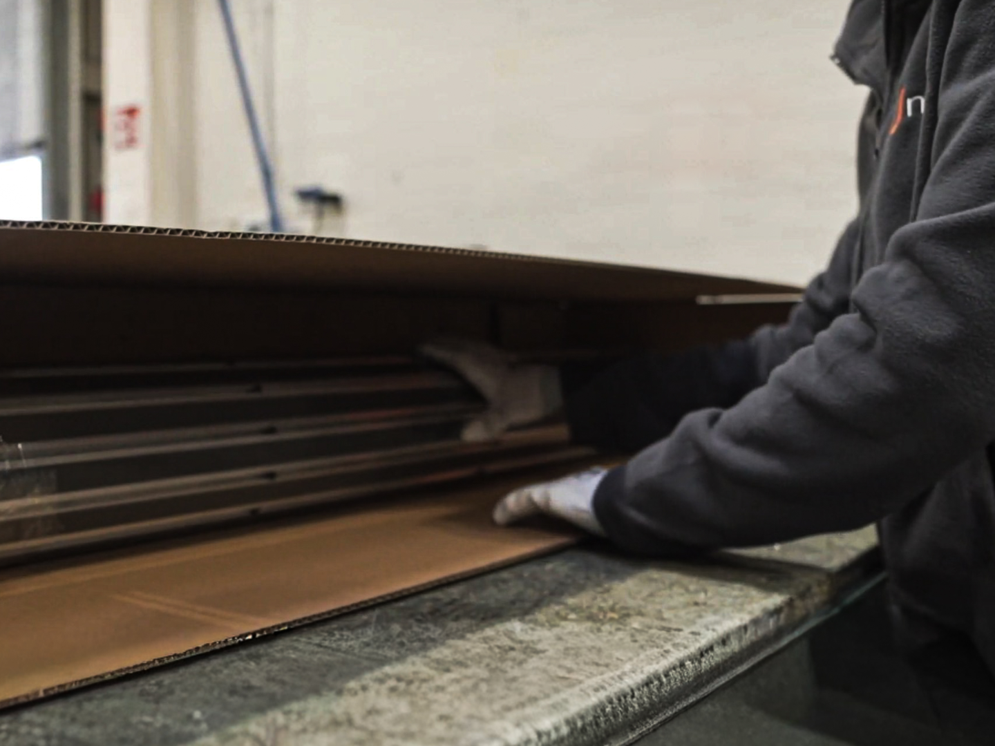 Mitarbeiter der ein Eingangsmattensystem in einen Karton verpackt