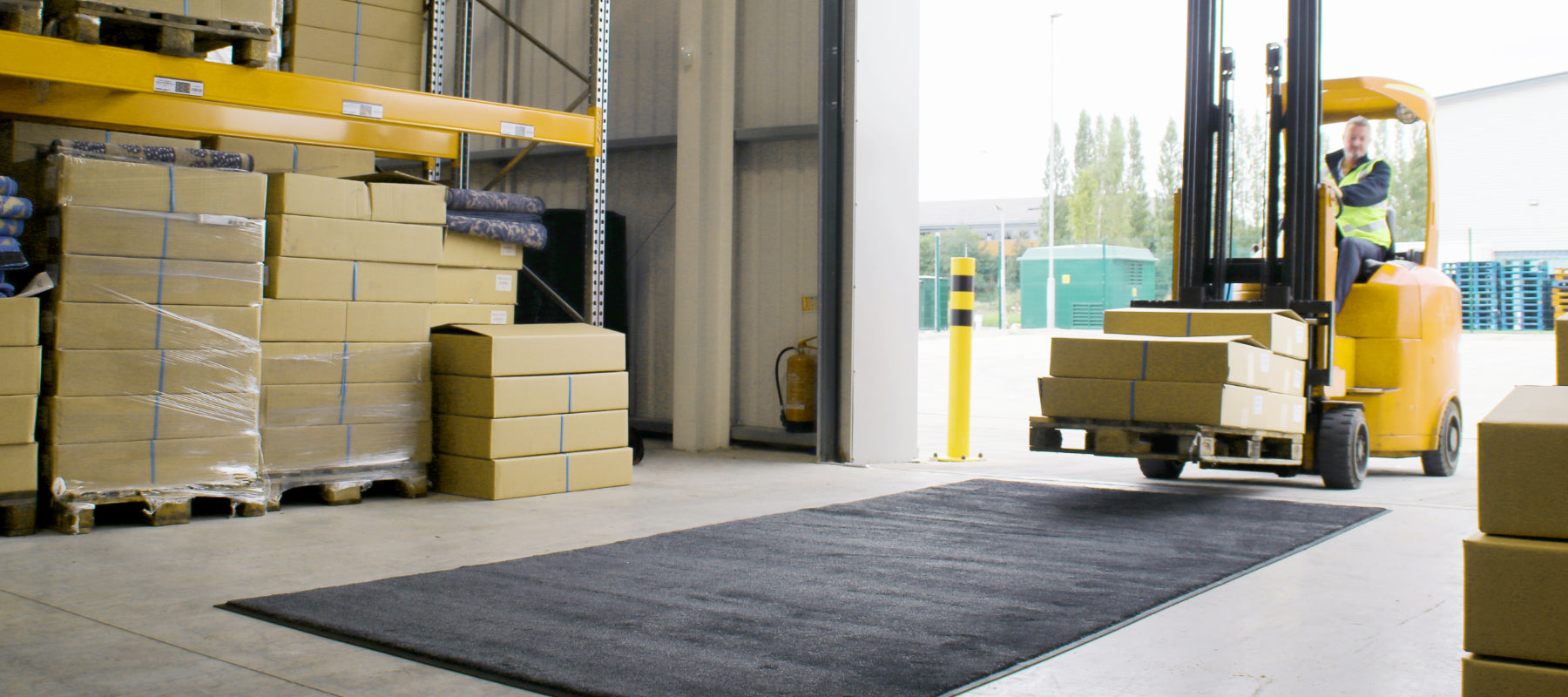 Lagerhalle mit einer Gabelstaplermatte auf der ein Gabelstapler zufährt