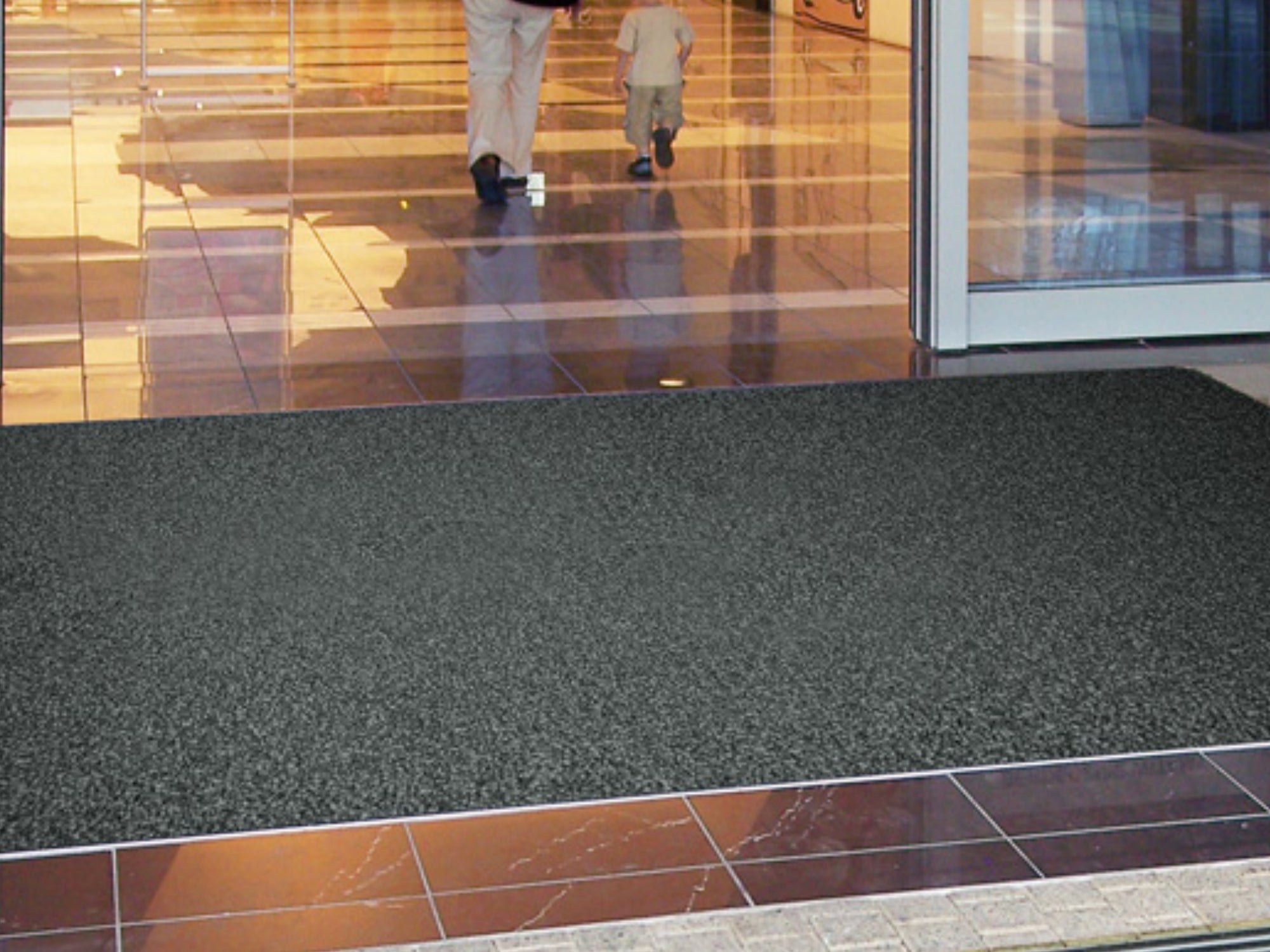 Schmutzfangmatte in Anthrazit liegt in Bodenvertiefung zwischen Fliesen im Eingangsbereich