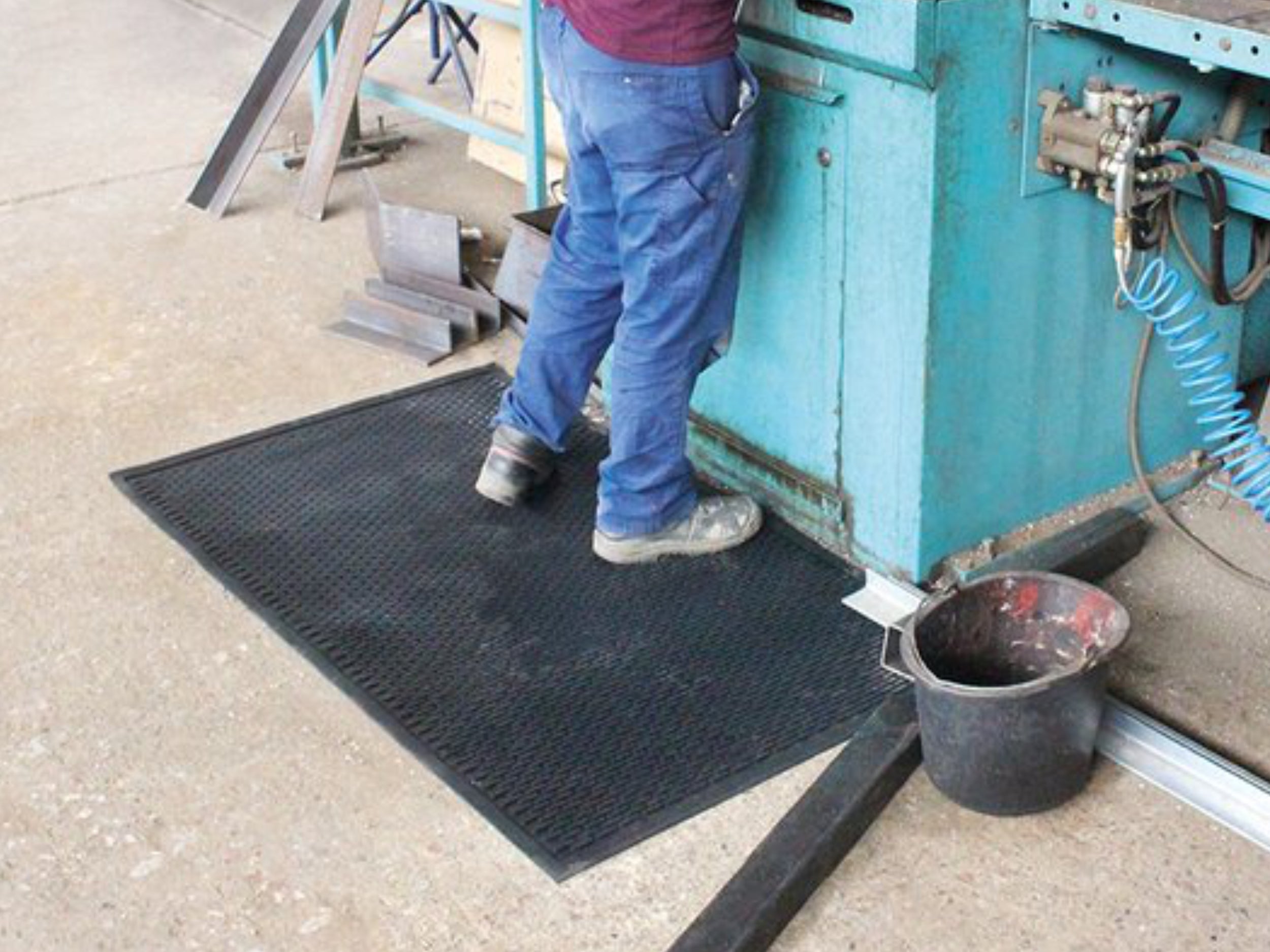 Arbeitsplatzmatte vor einer Werkbank auf dem ein Arbeiter Steht