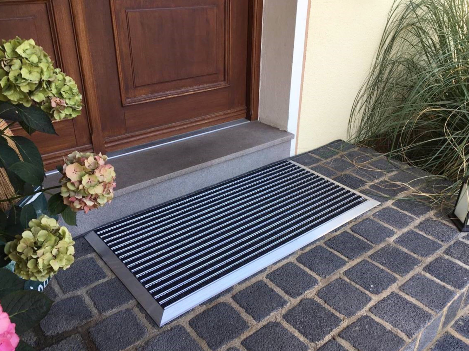 Aluprofilmatte mit Anlaufprofil vor Holztür eines Wohnhauses