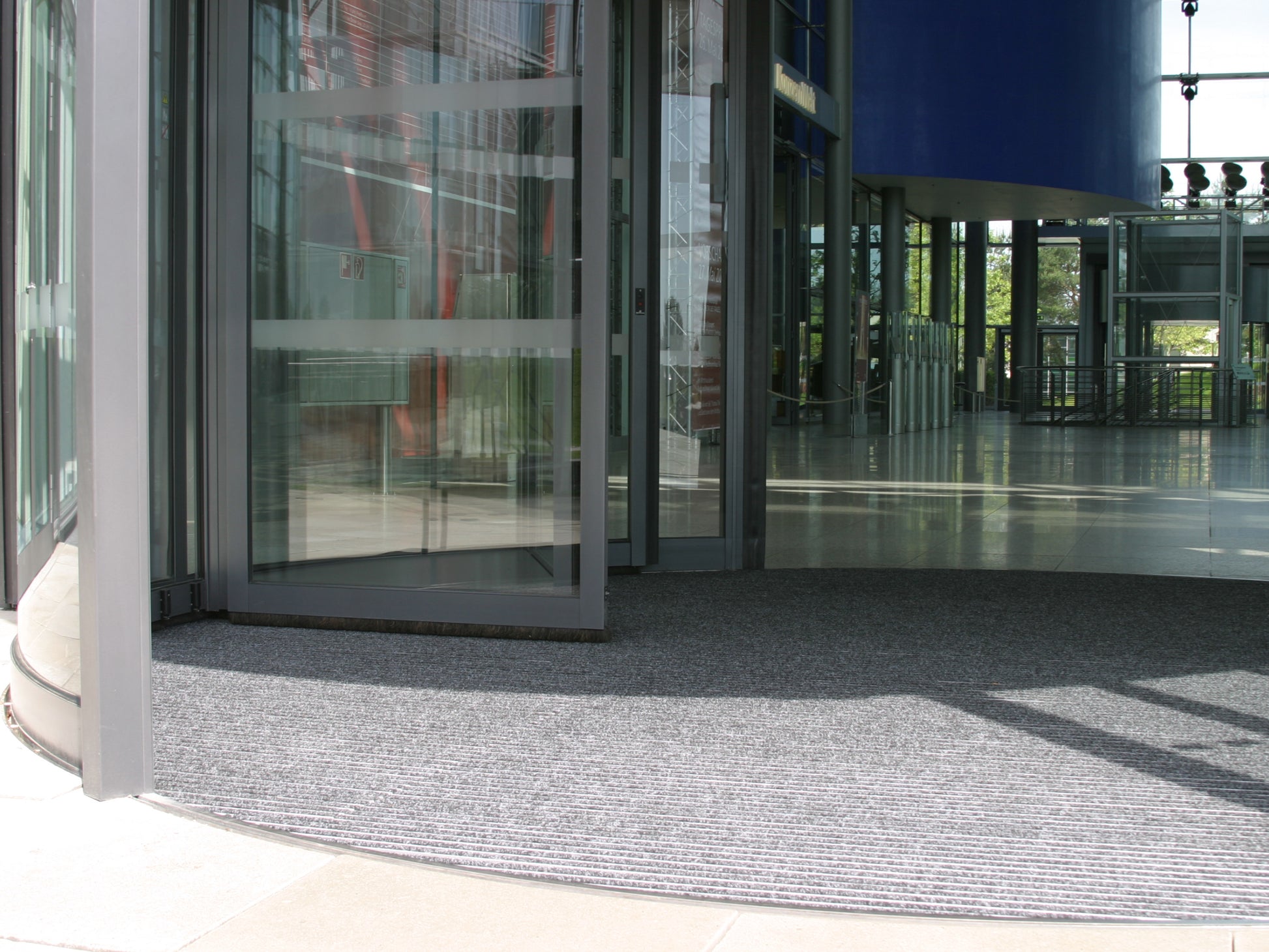 Eingangsbereich mit Drehtür – eine runde Aluprofilmatte ist im Boden eingelassen