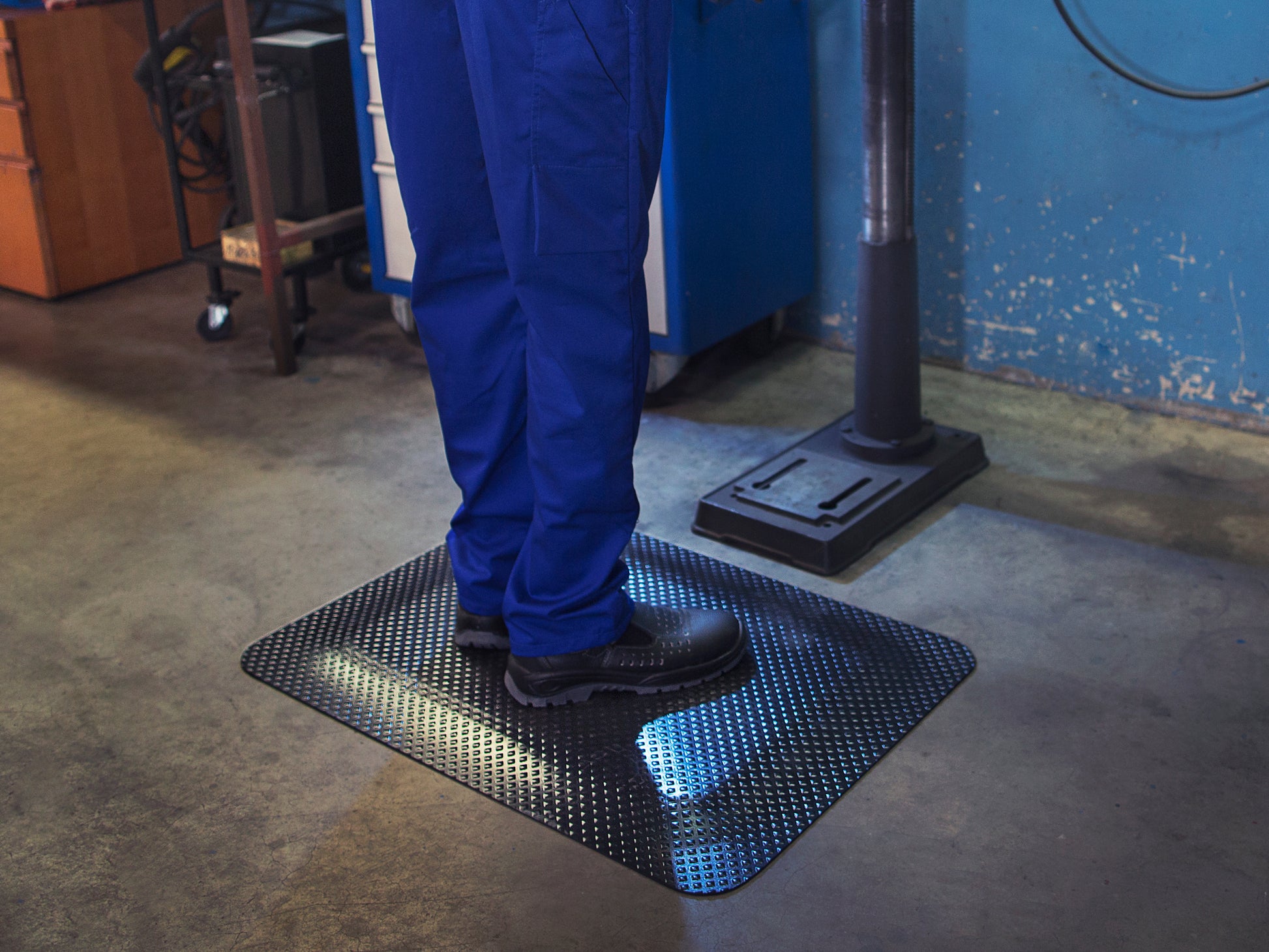 Arbeiter steht auf ergonomischer Gummi Arbeitsplatzmatte