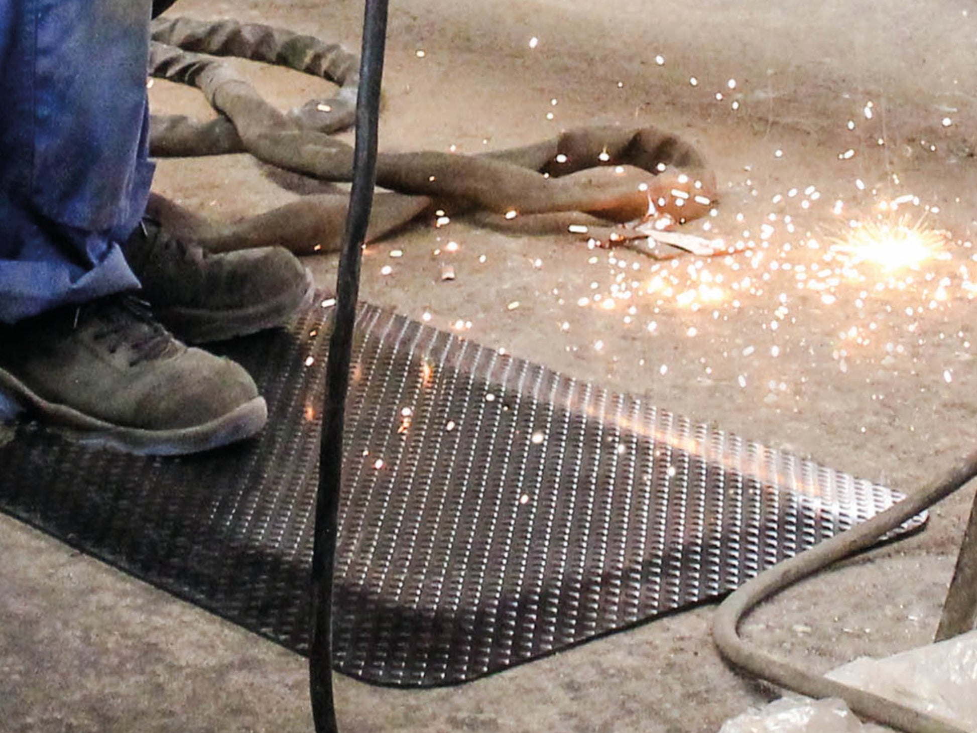 Nahaufnahme der ergonomischen Steharbeitsplatzmatte Ergo Work, Funken fliegen auf die Fußmatte