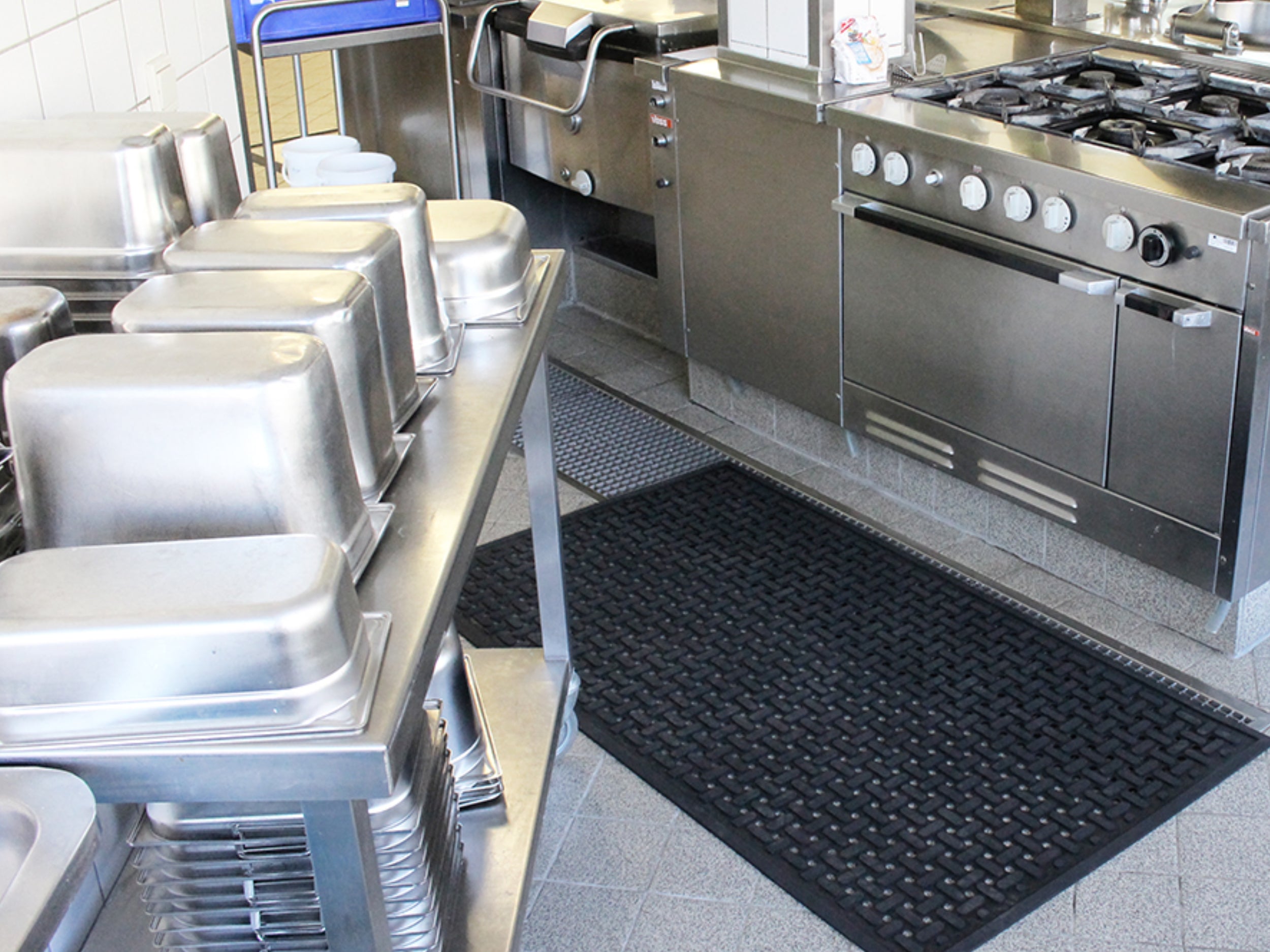 Arbeitsplatzmatte aus Gummi mit Drainagelöchern liegt auf dem Boden einer Großküche