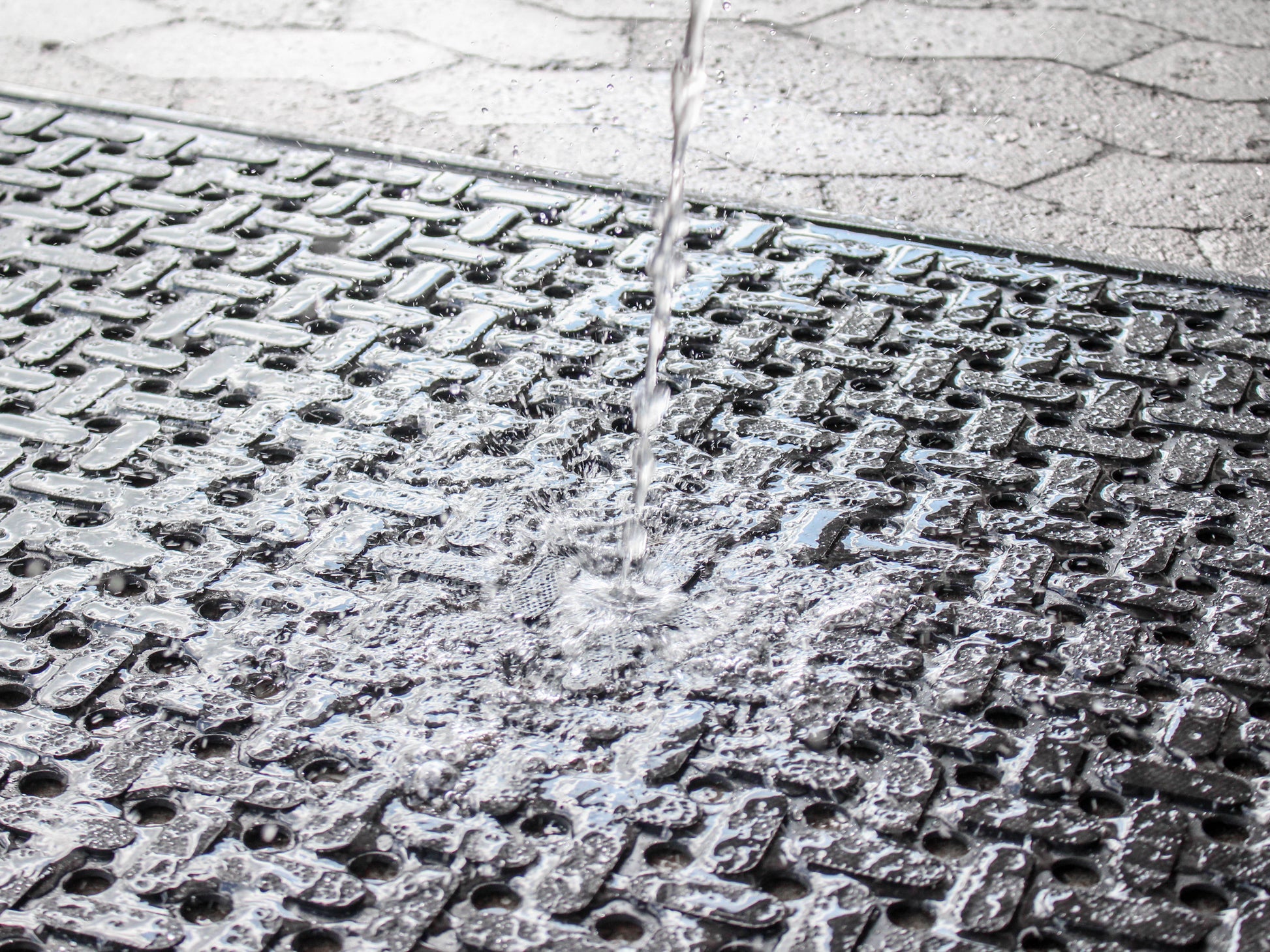 Nahaufnahme der Gummi Arbeitsplatzmatte Pro Water, auf die ein Wasserstrahl gerichtet ist