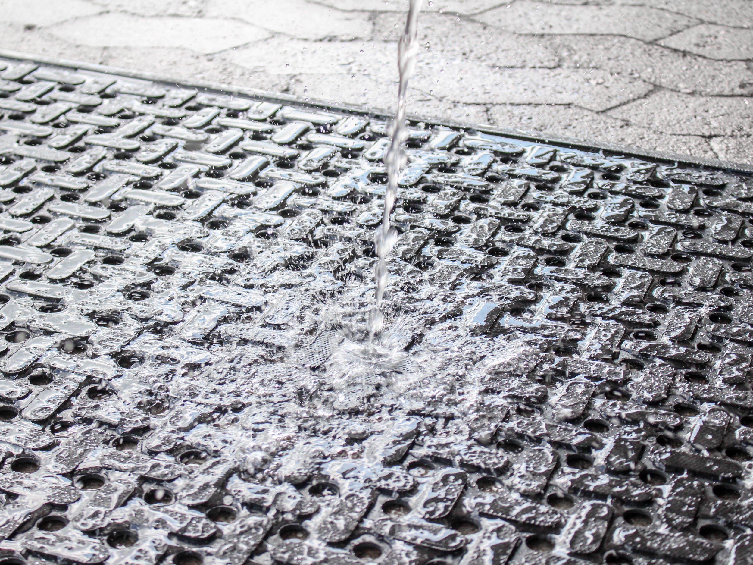 Nahaufnahme der Gummi Arbeitsplatzmatte Pro Water, auf die ein Wasserstrahl gerichtet ist