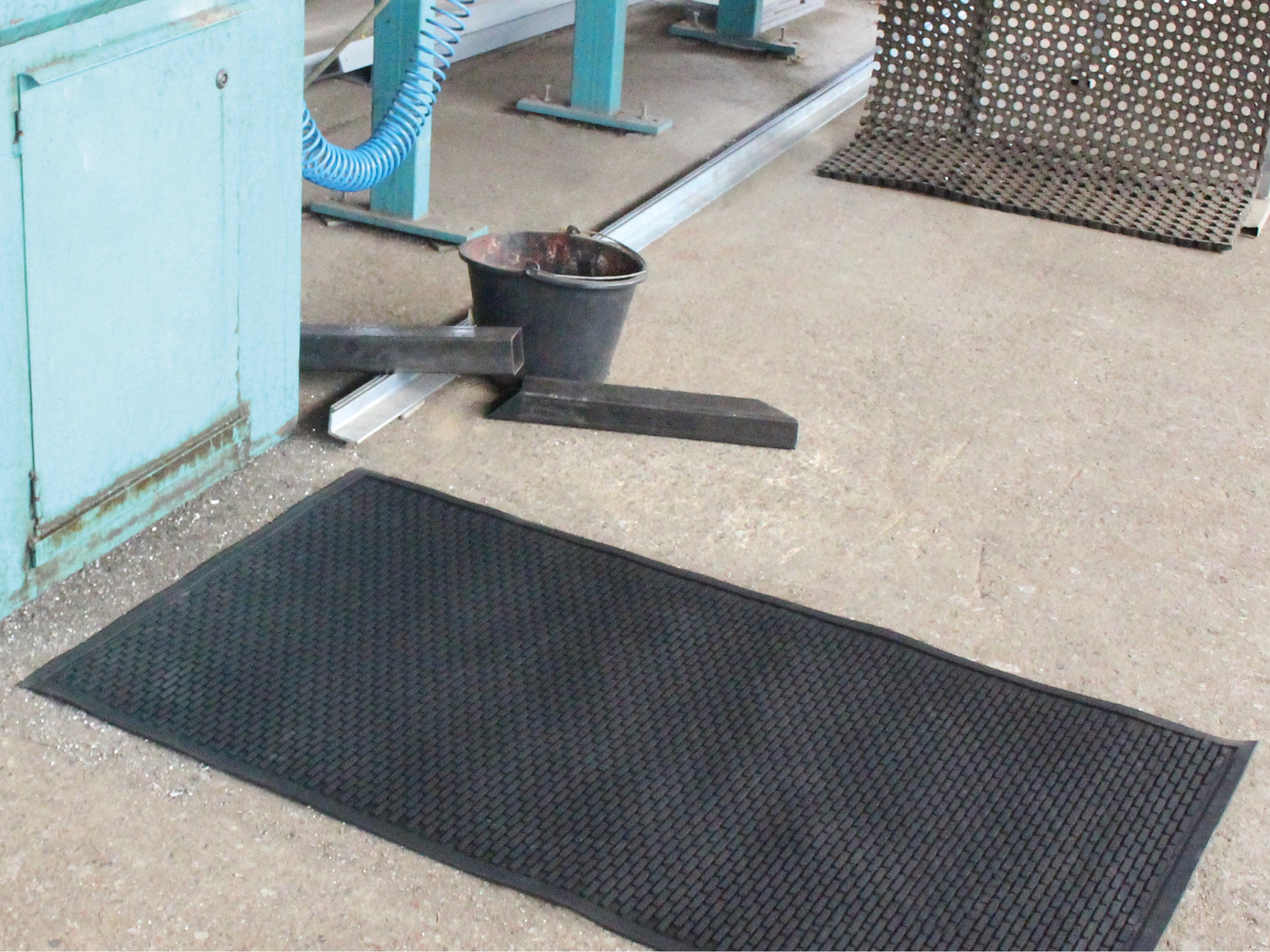 Arbeitsplatzmatte Pro Work mit strukturierter Gummioberfläche liegt in Industriehalle vor einem Arbeitsplatz