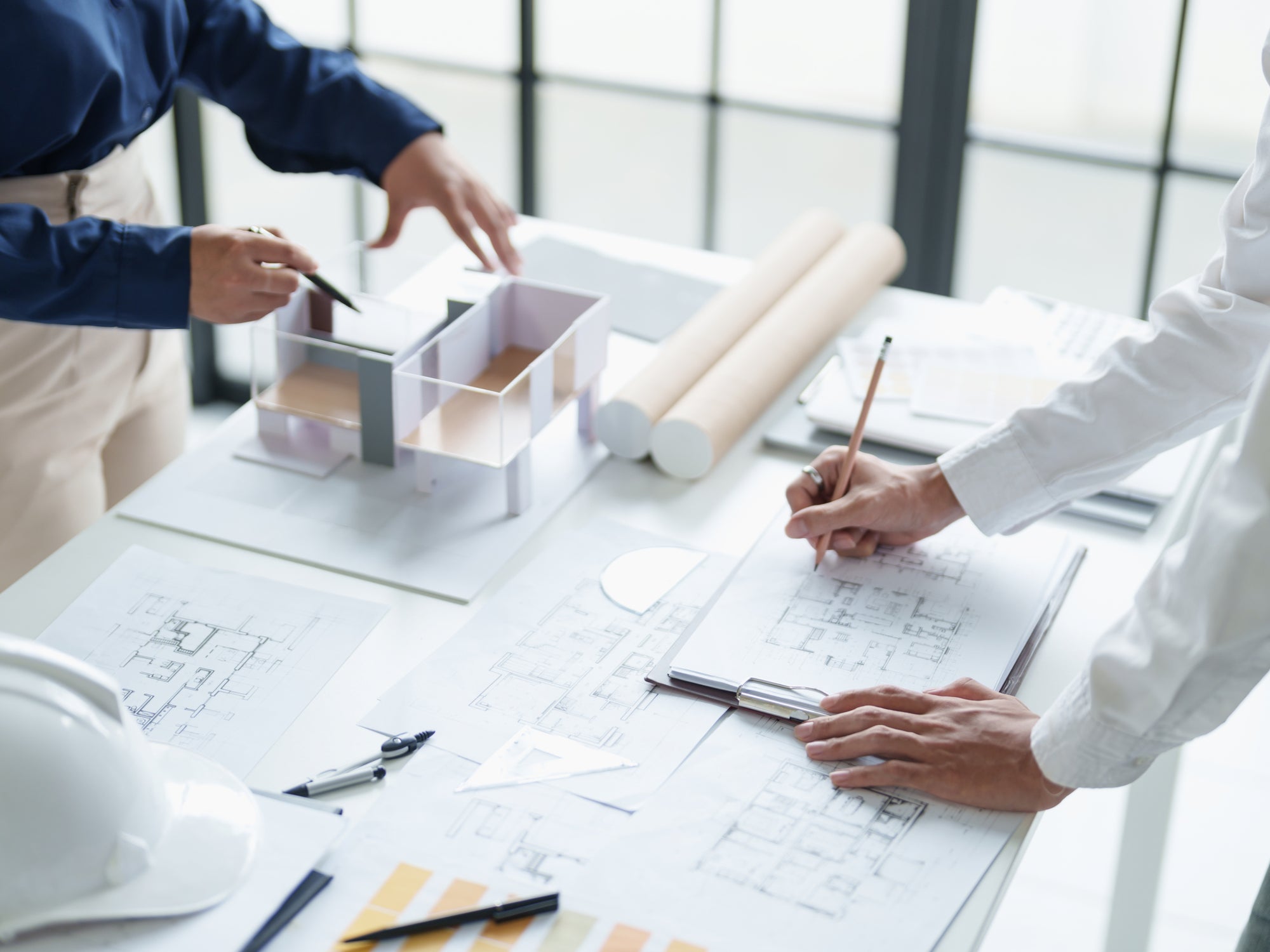 Architekten planen ein Gebäude mit Modell und Bauplänen