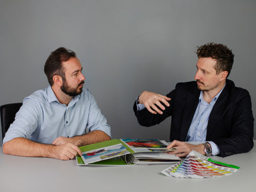 Beratungsgespräch zu einem Teppichprodukt mit Farbmustern und Katalog
