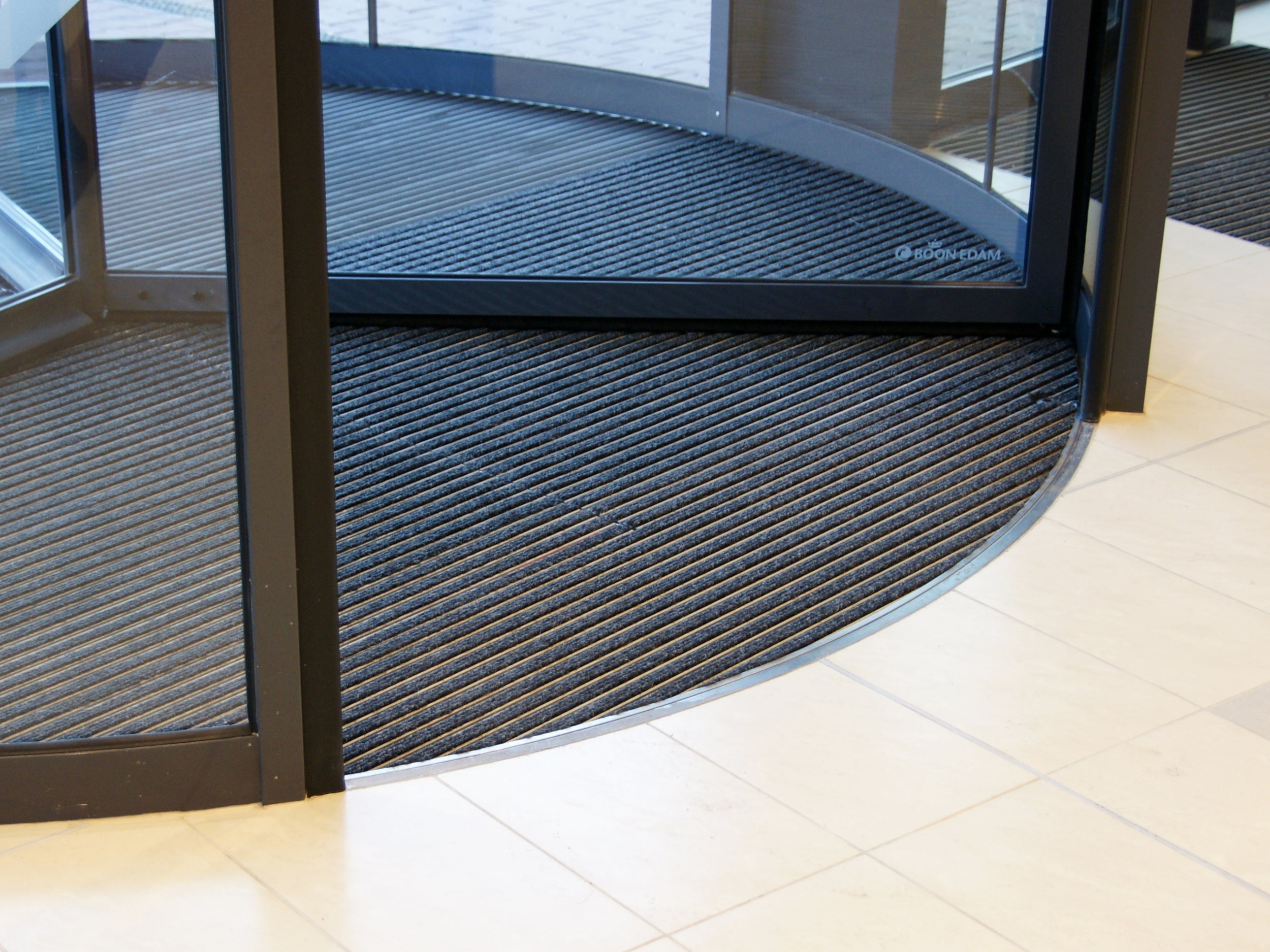 Drehtür mit Aluprofilmatte und Abdeckschiene aus Edelstahl als Übergang zwischen Fußmatte und Fliesenboden