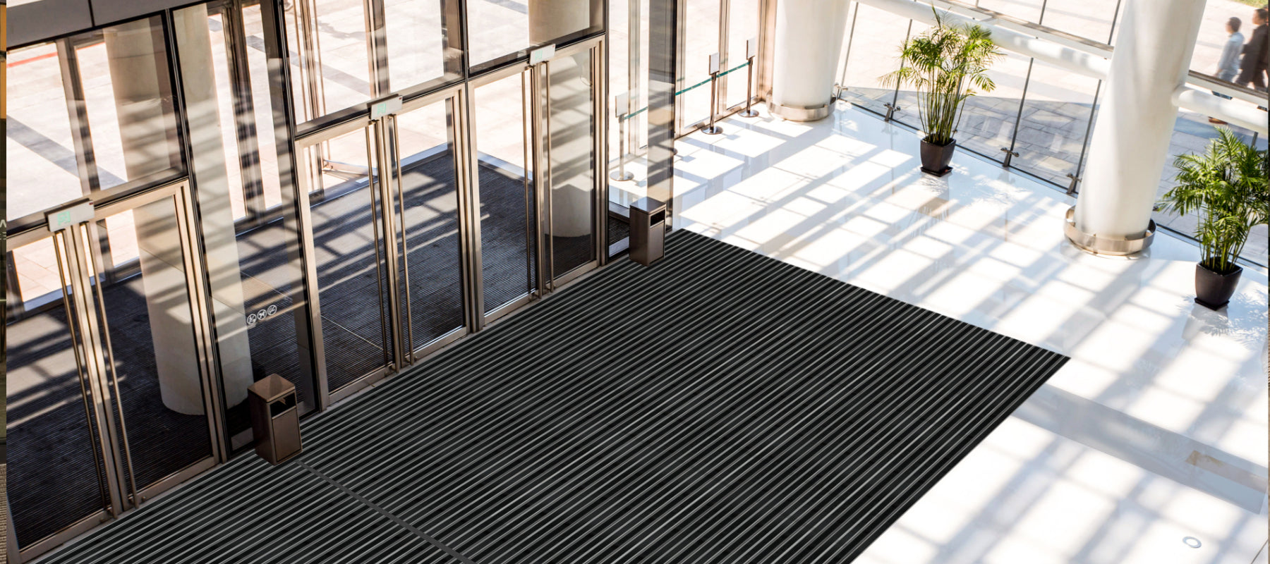 Ein einem großen Foyer mit Glasfront und weißem Boden liegt eine Aluprofilmatte in schwarz