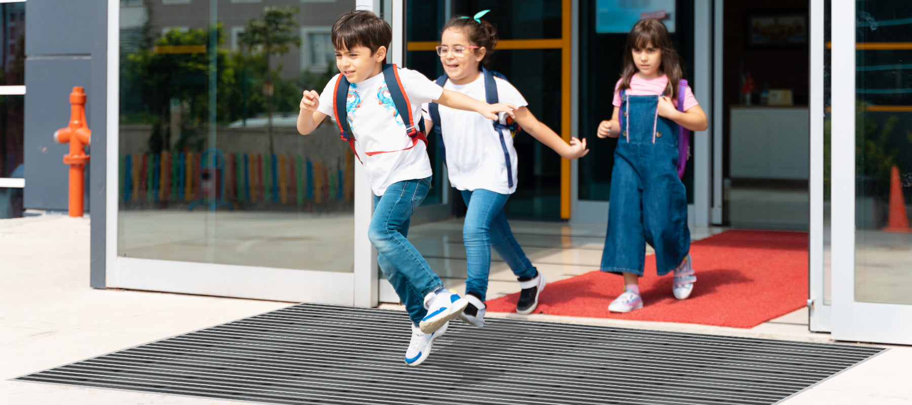 Kinder laufen aus Gebäude über eine Fußmatte raus