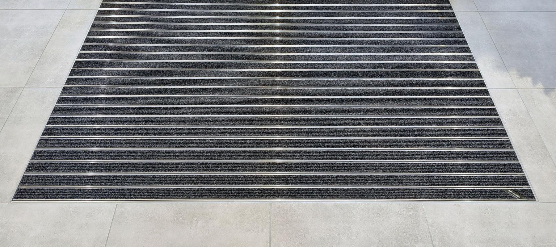 Aluprofilmatte mit Ripseinlage in anthrazit mit Rahmen ist in einem grauen Fliesenboden integriert