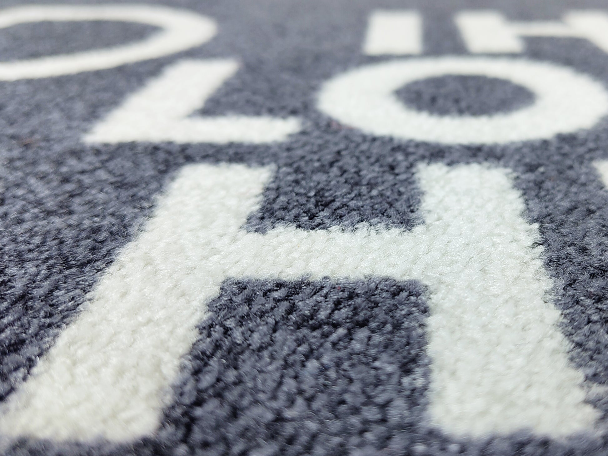 Nahaufnahme einer Logomatte anthrazit mit Schriftbild in Weiß