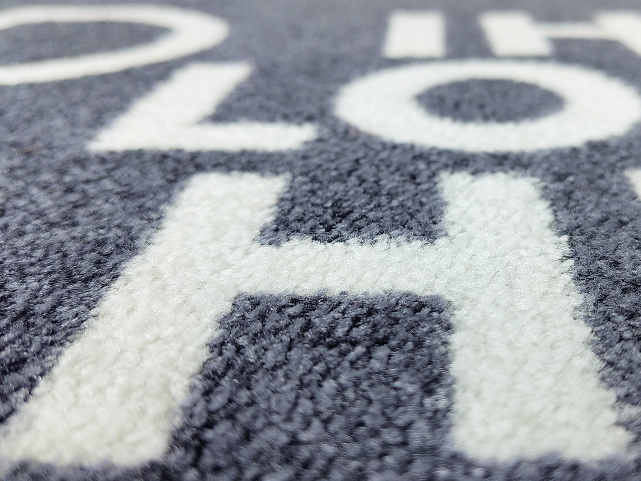 Nahaufnahme einer Logomatte anthrazit mit Schriftbild in Weiß