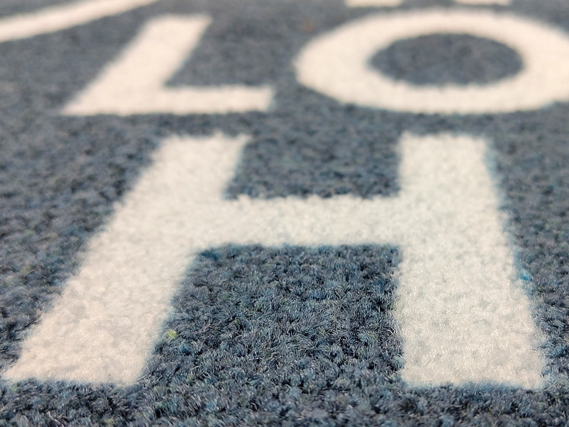 Weißer Schriftzug auf grauer Logomatte als Nahaufnahme