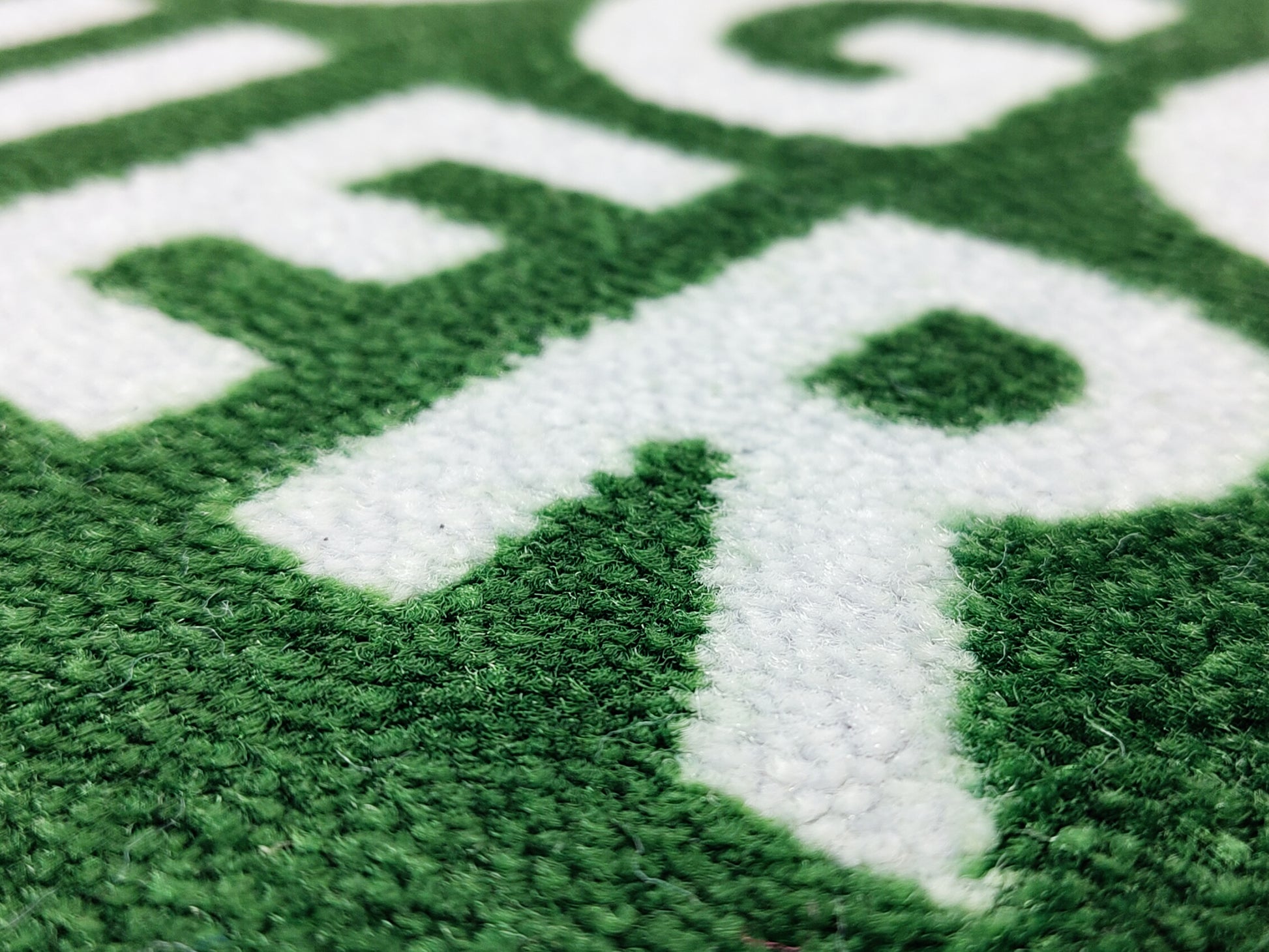 Nachaufnahme des Druckbildes einer grünen Logomatte mit weißer Schrift