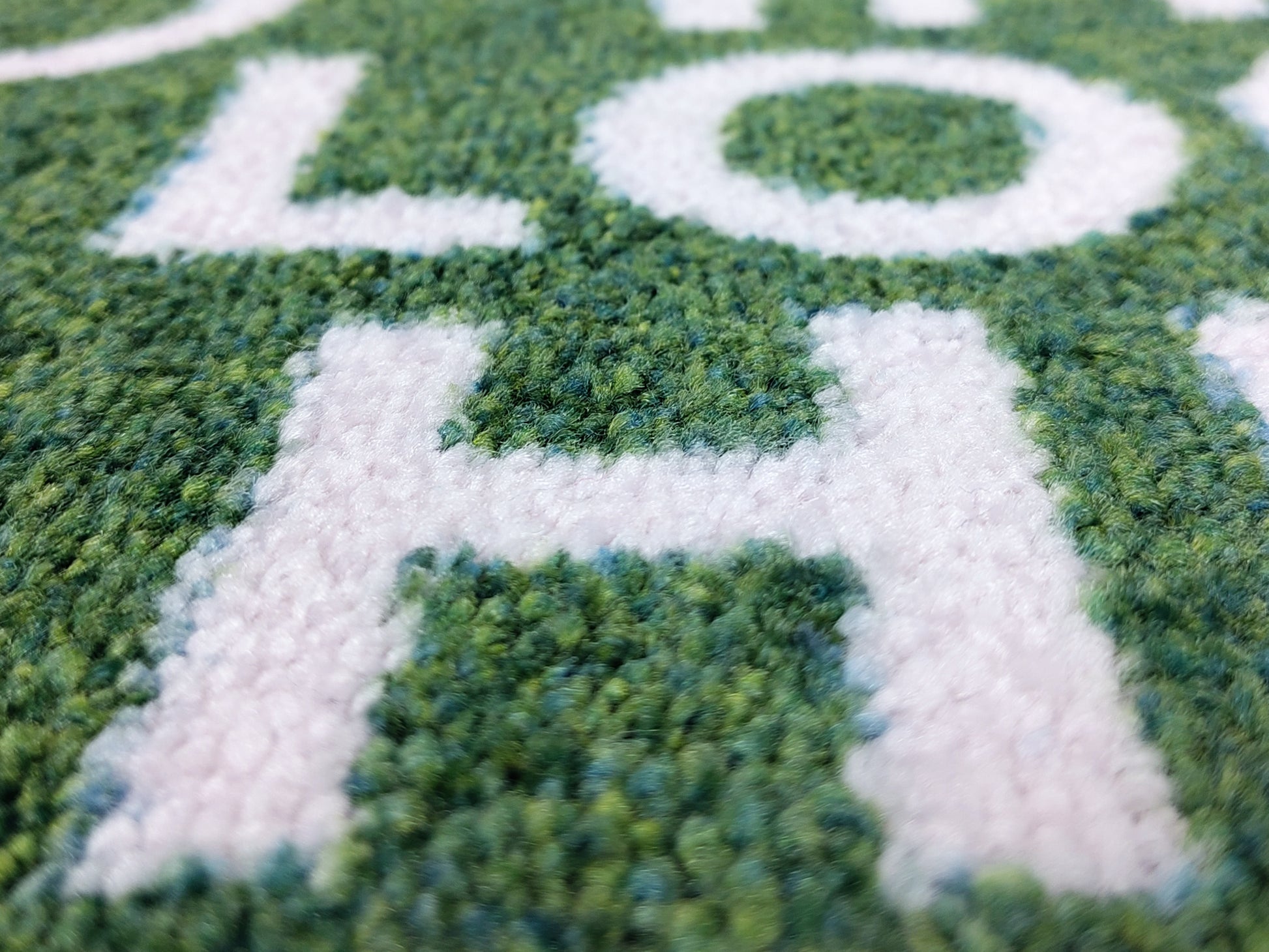 Nahaufnahme des Druckbildes einer nachhaltigen und grünen Logomatte mit weißer Schrift