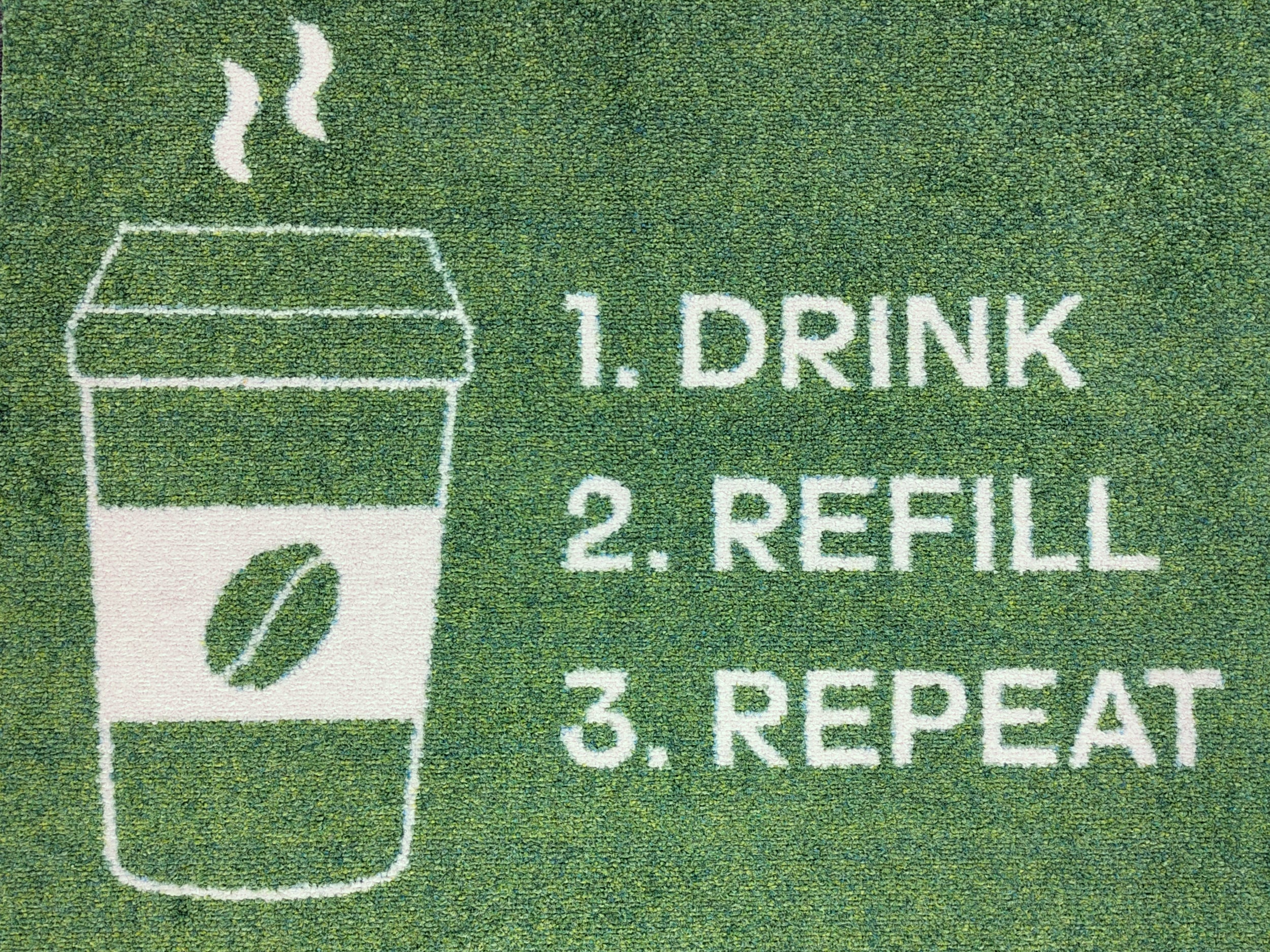 Nahaufnahme des Druckbildes einer nachhaltigen und grünen Logomatte mit weißer Schrift: Drink, Refill, Repeat
