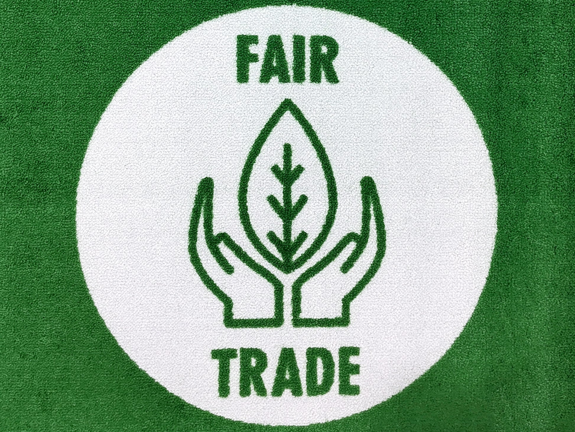 Fair Trade Badge auf einer grünen und nachhaltigen Logomatte