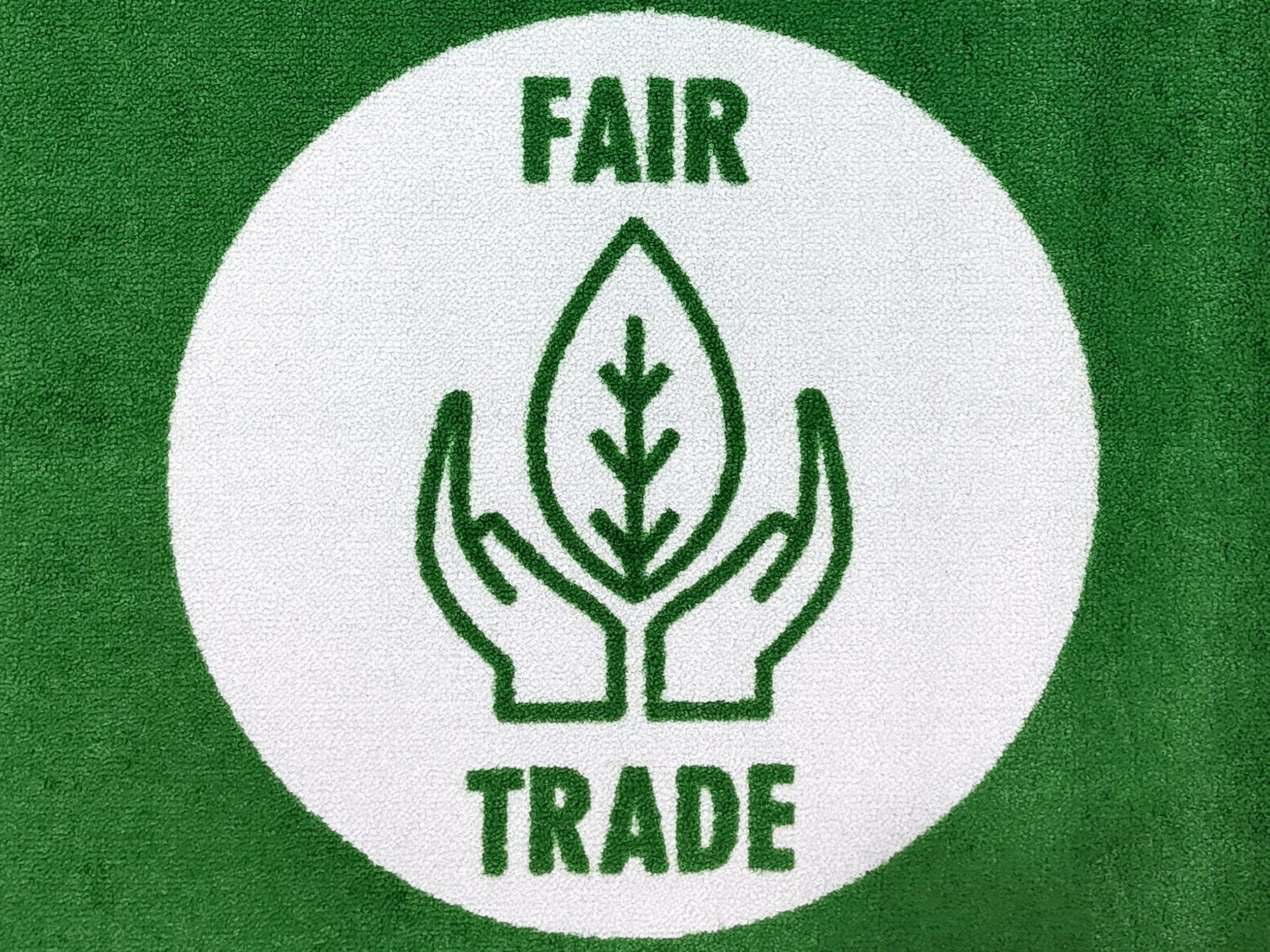 Fair Trade Badge auf einer grünen und nachhaltigen Logomatte