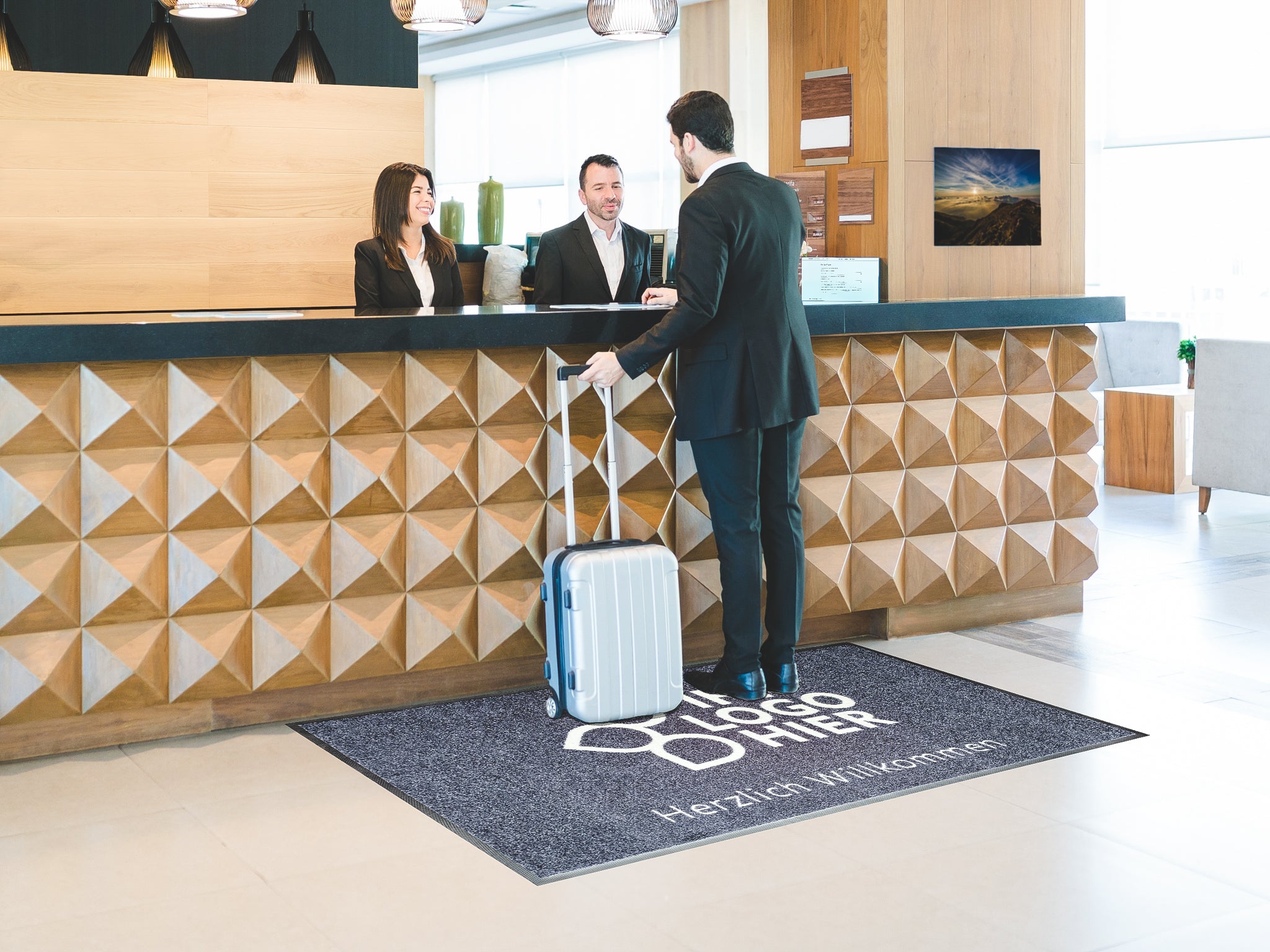 Individualisierbare Logomatte in einer Lobby liegend mit dem Schriftzug: Ihr Logo hier und Herzlich Willkommen