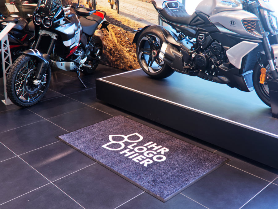 Logomatte mit dem Aufdruck IHR LOGO HIER in einem Mottorradhaus am POS