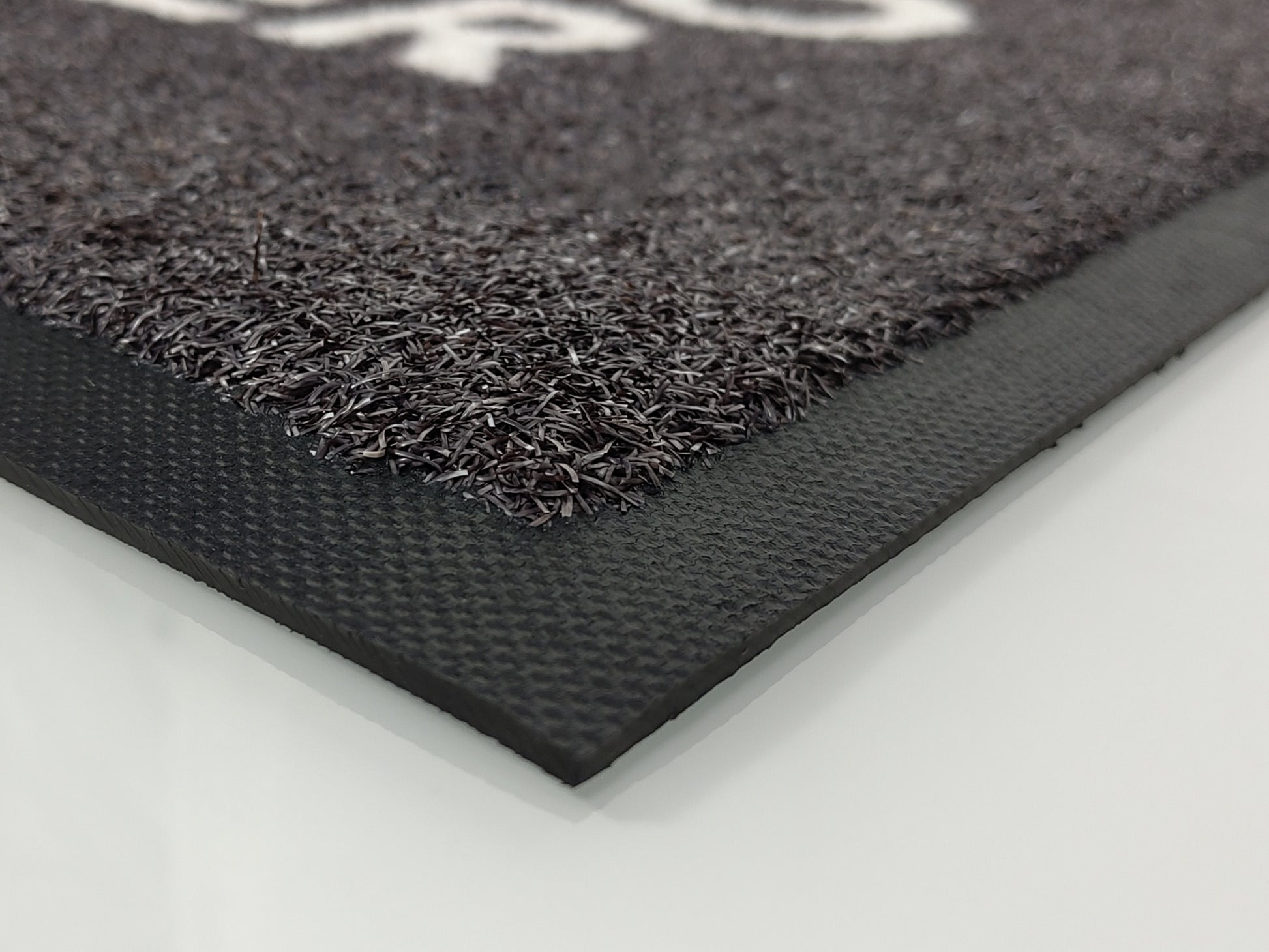 Der Gummirand einer Matte, die relativ breit ausfällt. Die Matte zeigt eine grobe Struktur.