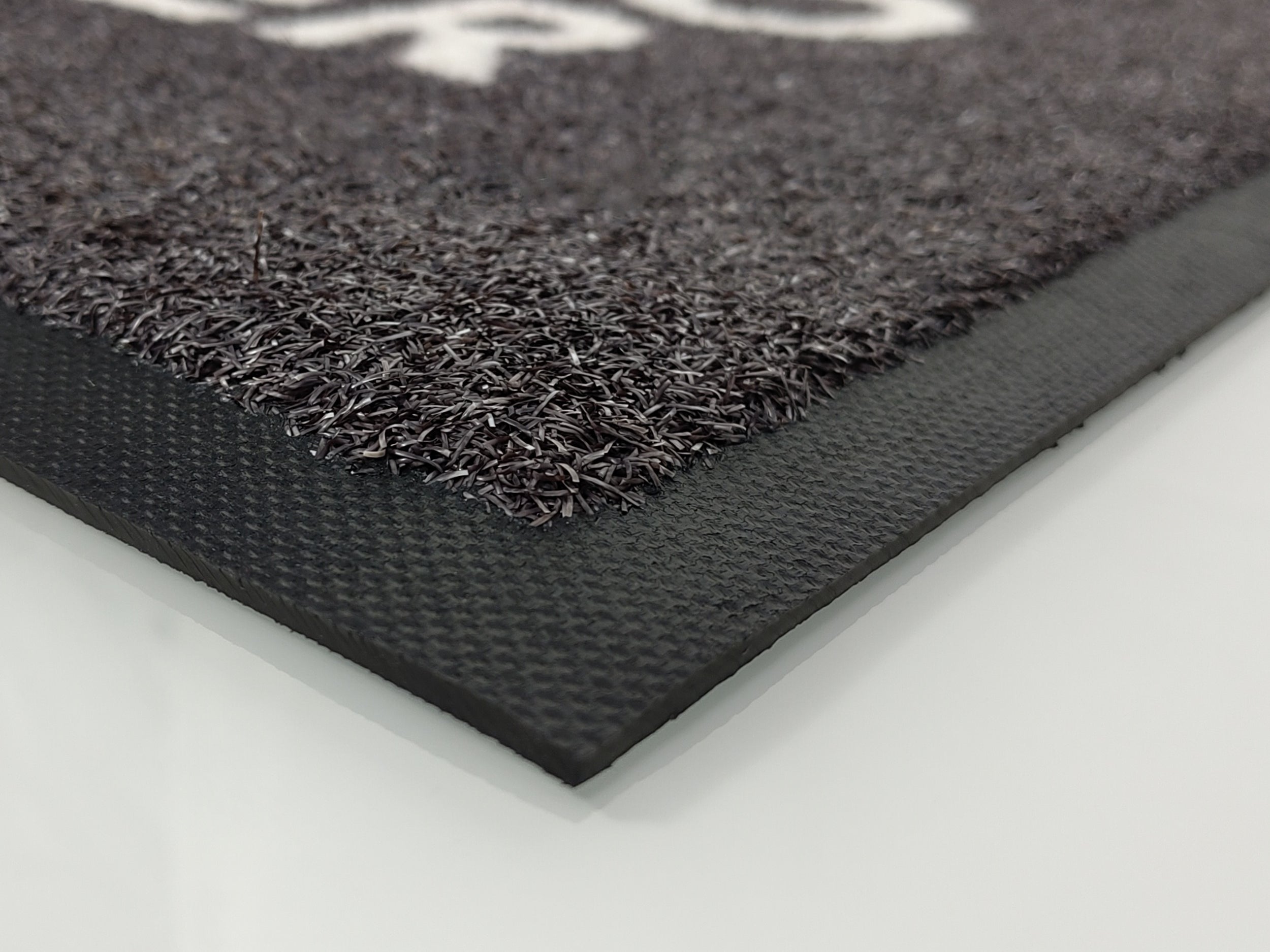 Der Gummirand einer Matte, die relativ breit ausfällt. Die Matte zeigt eine grobe Struktur.