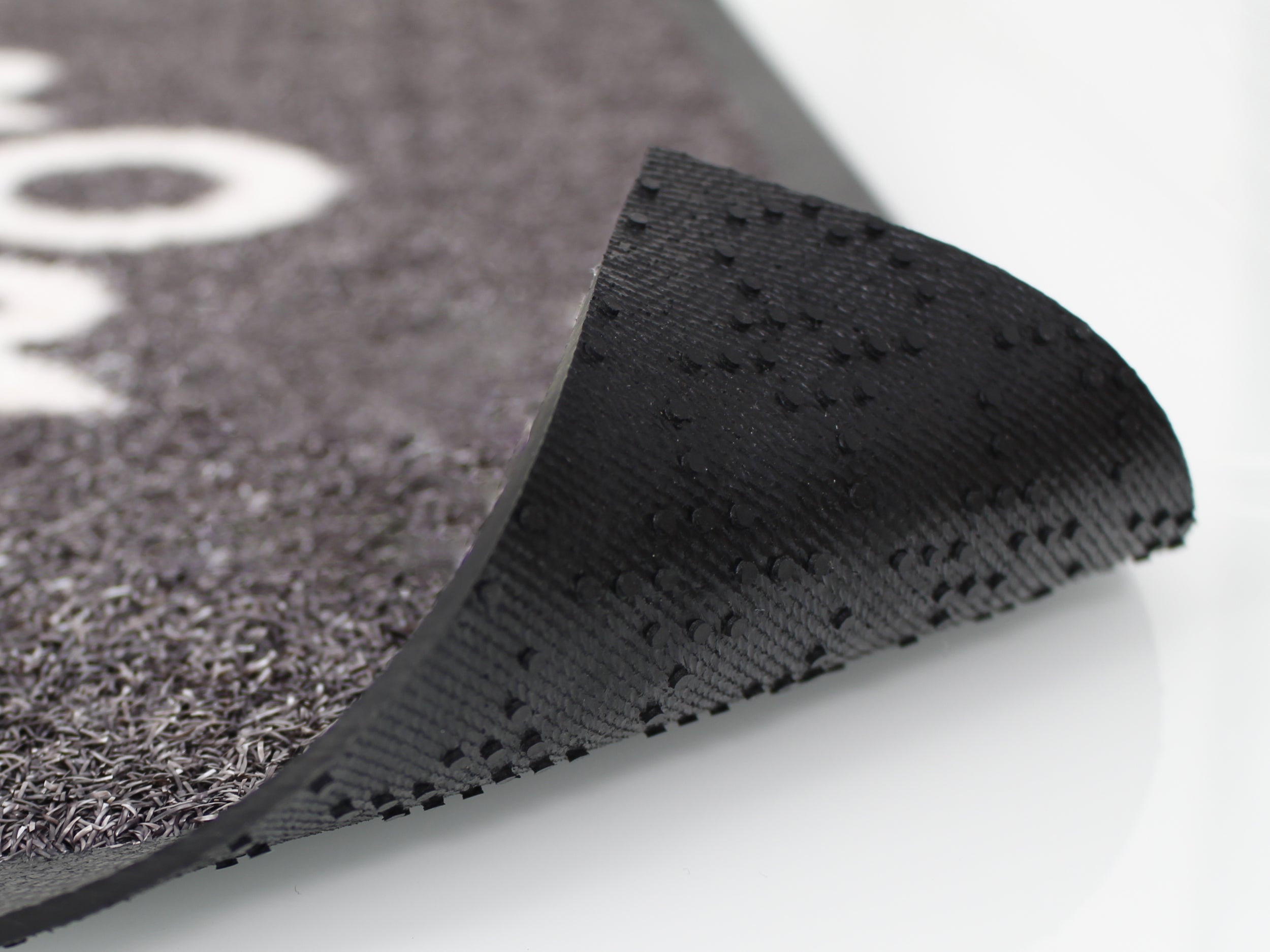 Dieses Bild zeigt eine hochgeklappte Matte, die eben die noppige, gummiartige Rückseite dessen zur schau bringt. 