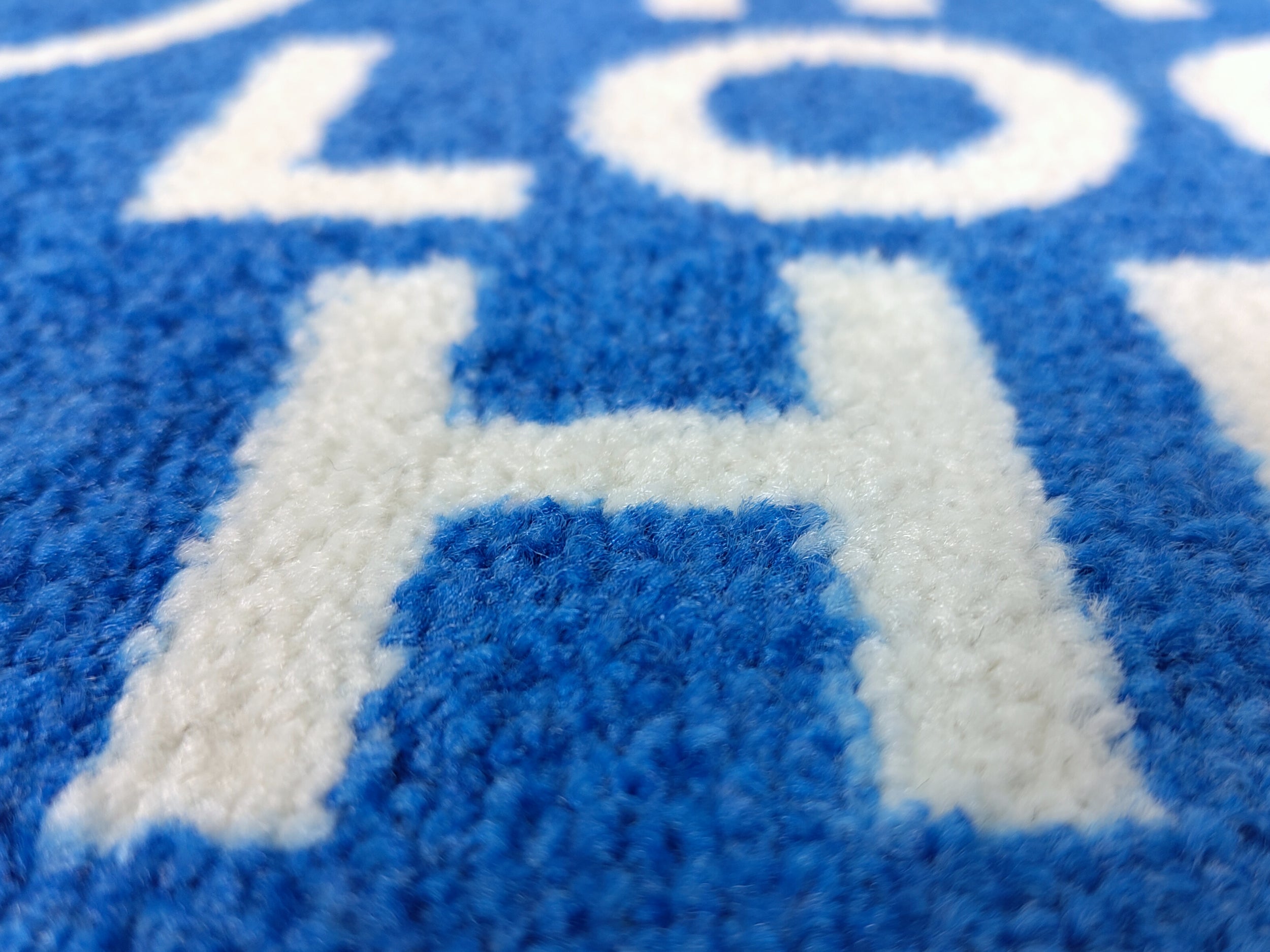 Nahaufnahme des Druckbildes einer blauen, kurzfristig verfügbaren Logomatte mit weißer Schrift