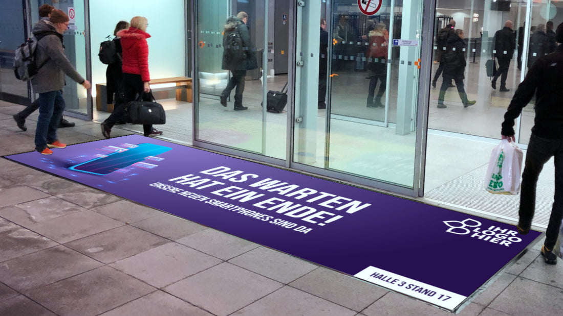 Messeteppich mit Handymotiv vor dem Eingang einer Messehalle