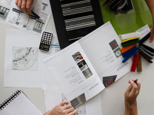 Tisch aus der Vogelperspektive mit technischen Zeichnungen und Produkten