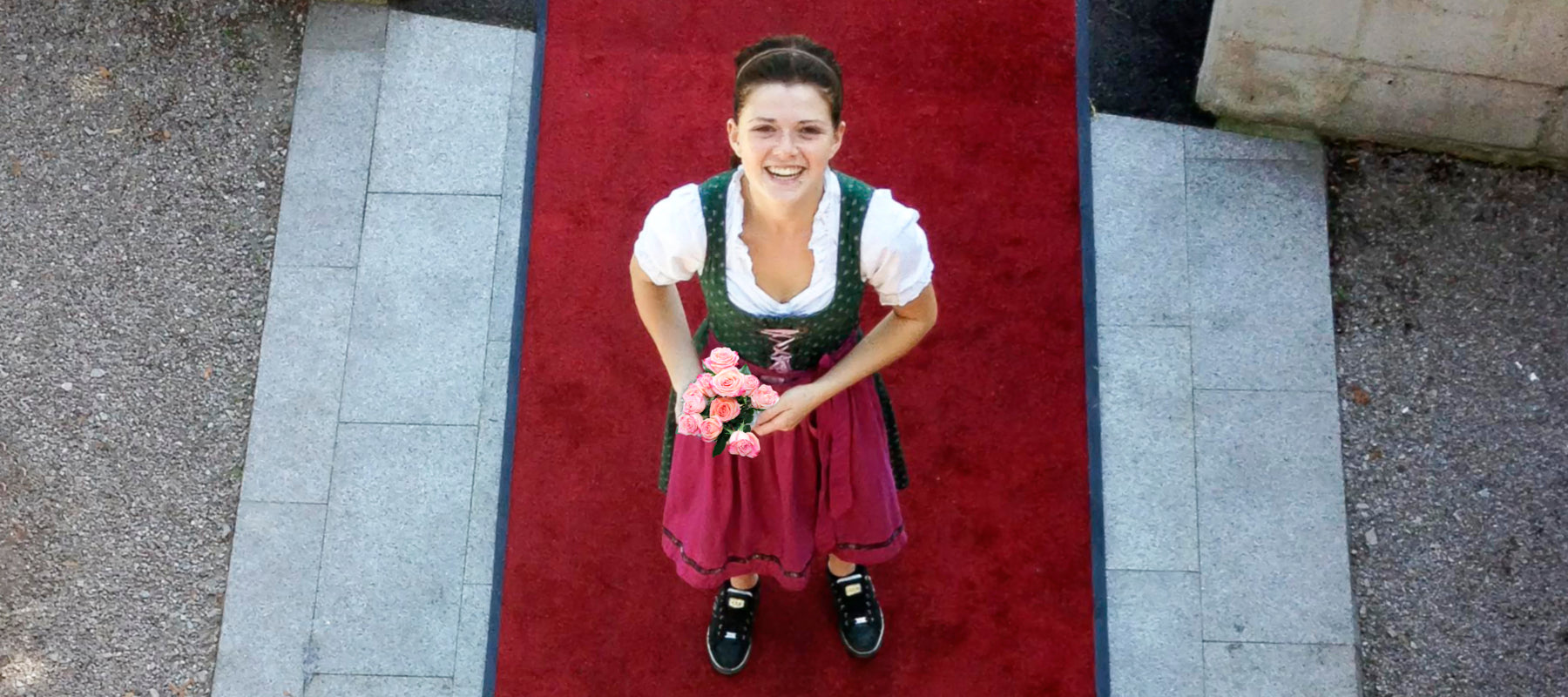 Frau steht im Außenbereich auf einem rotem Outdoor Teppch