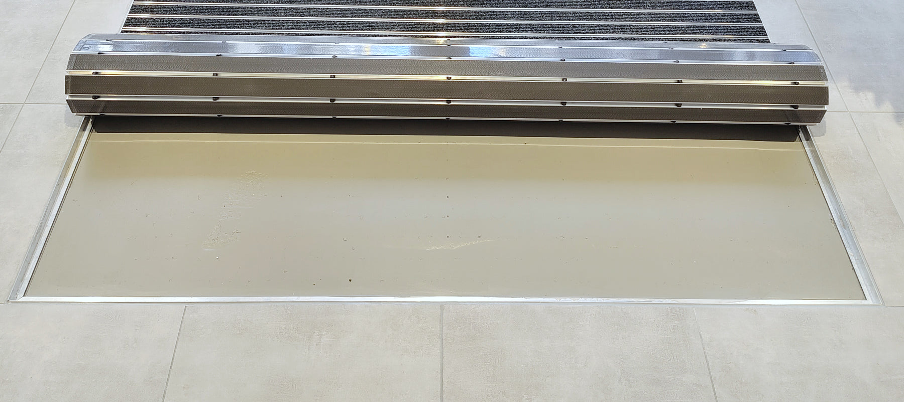 Bodenvertiefung mit Einbaurahmen in der eine aufgerollte Matte liegt