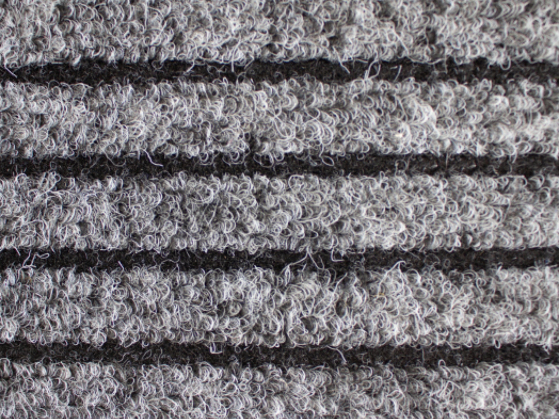 Nahaufnahme der Textur einer Fußmatte aus Rauhaarrips in grau