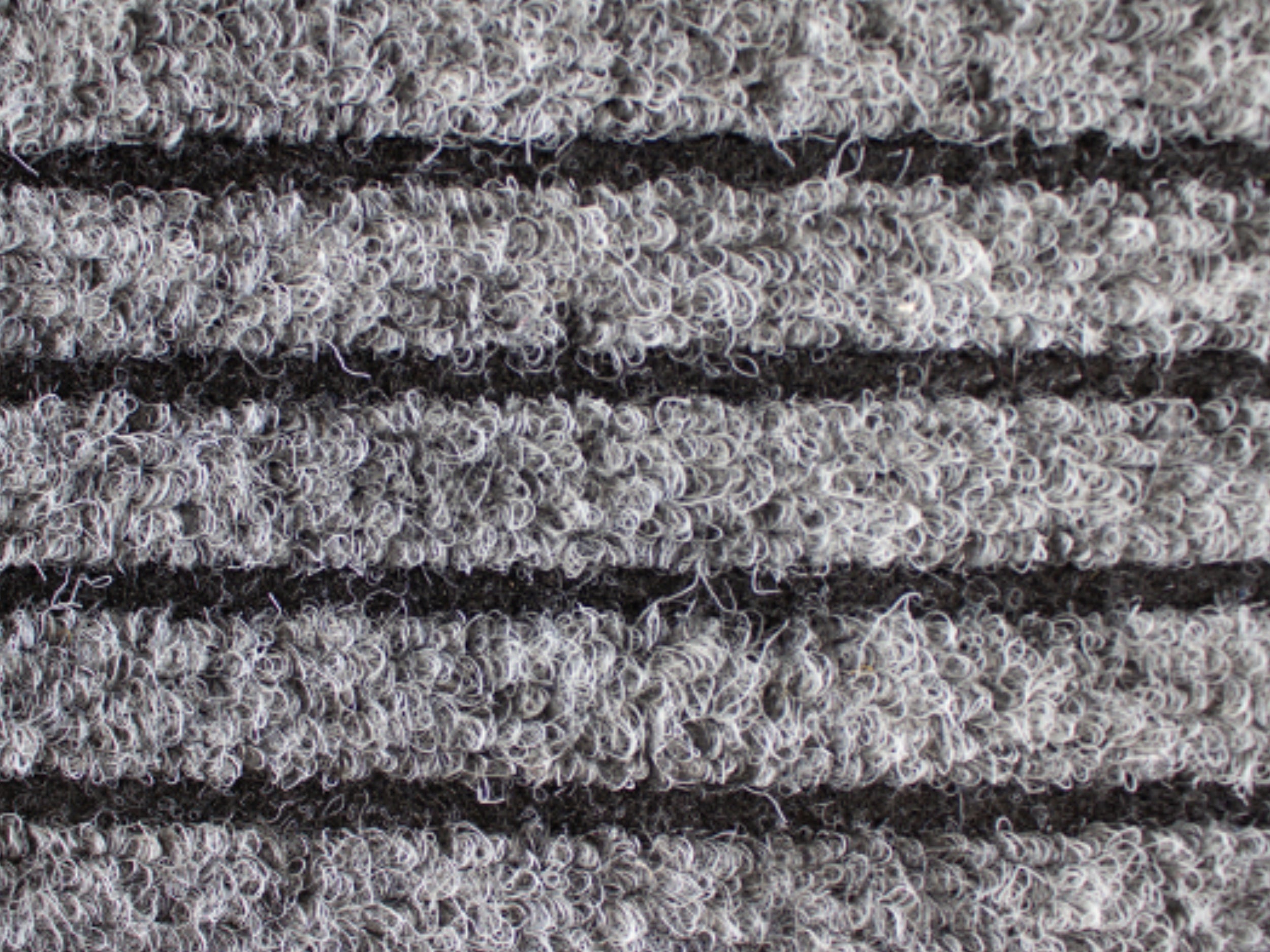Nahaufnahme der Textur einer Fußmatte aus Rauhaarrips in grau