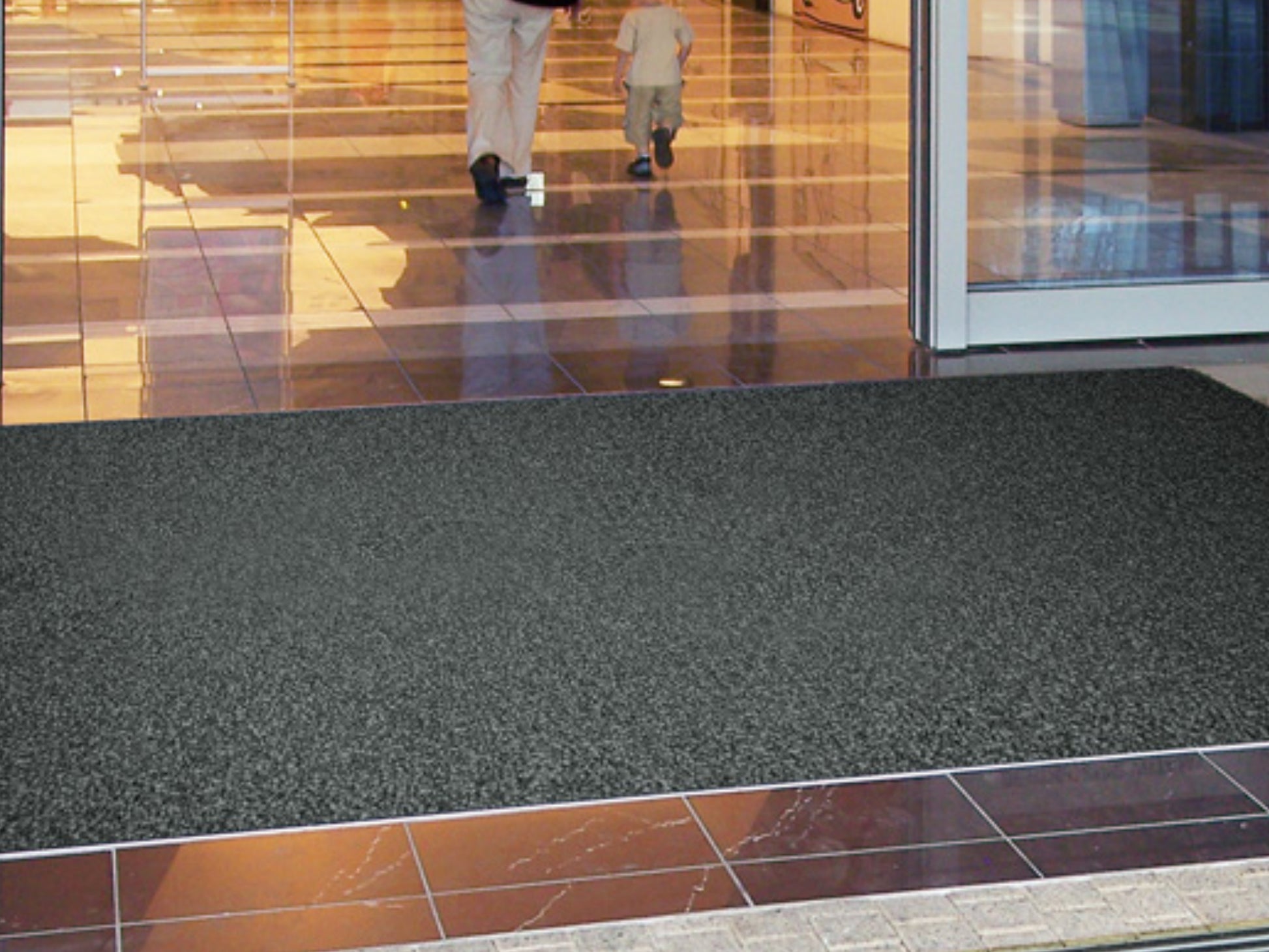 Schmutzfangmatte in Anthrazit liegt in Bodenvertiefung zwischen Fliesen im Eingangsbereich