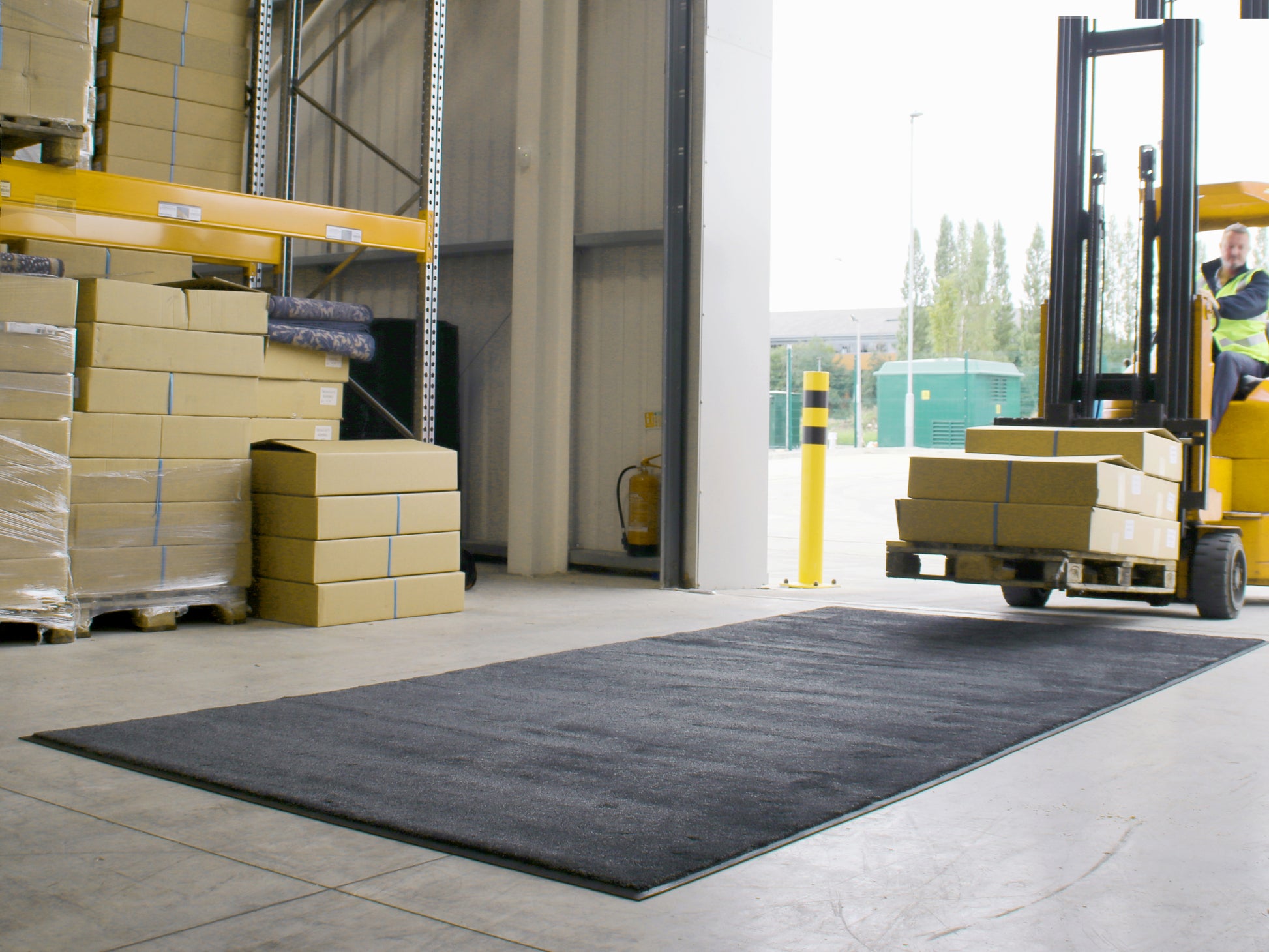 Befahrbare Schmutzfangmatte liegt im Eingangsbereich eine Logistikhalle: Ein Gabelstabler fährt darüber