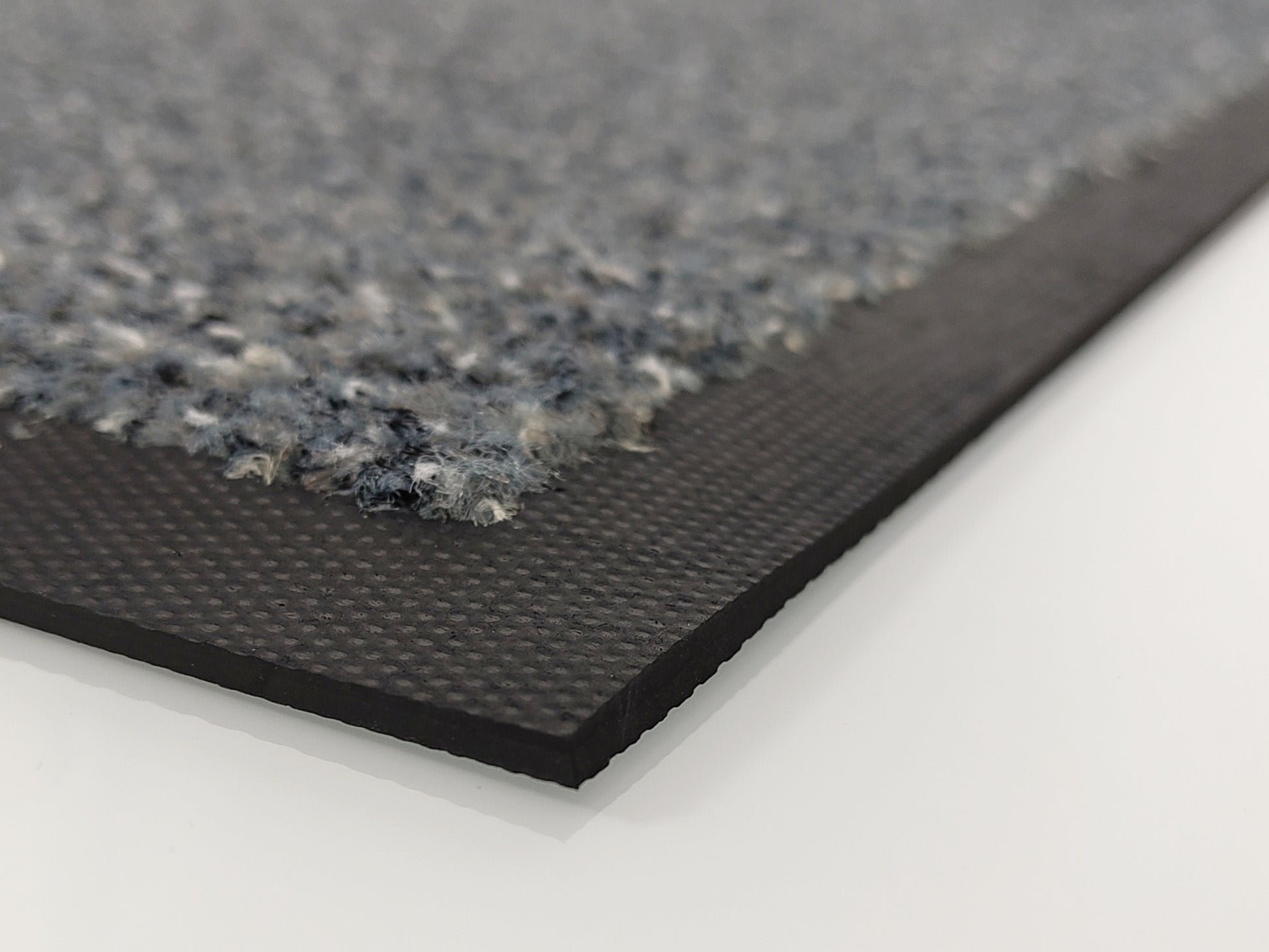 Ecke einer grauen Schmutzfangmatte mit Kratzfasern und Rand