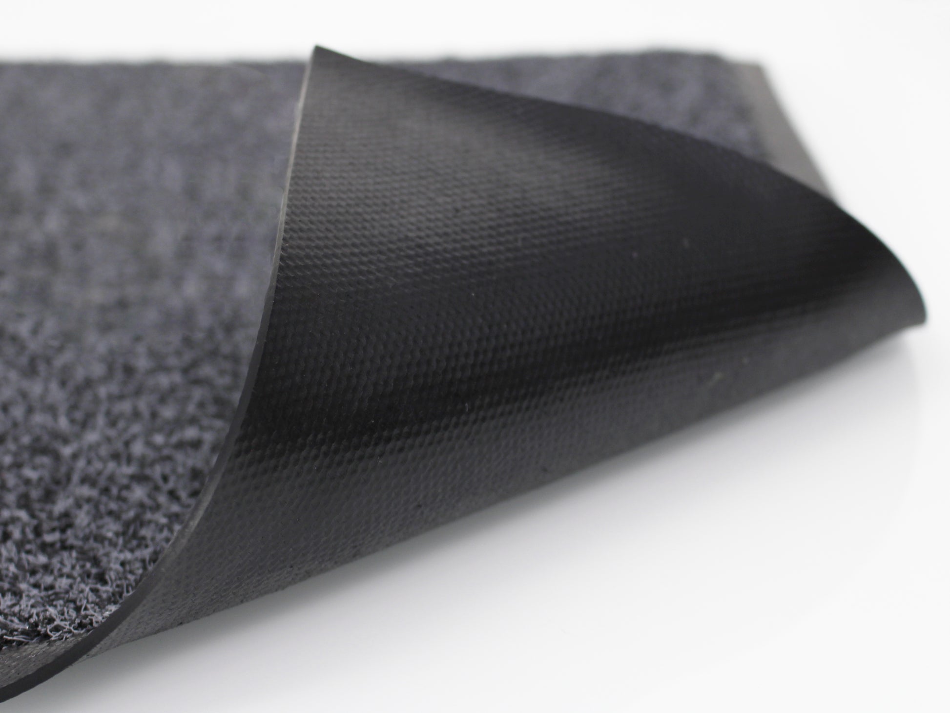 Schwarzes Gummi-Rückenmaterial einer umgeklappten Schmutzfangmatte für den Outdoorbereich