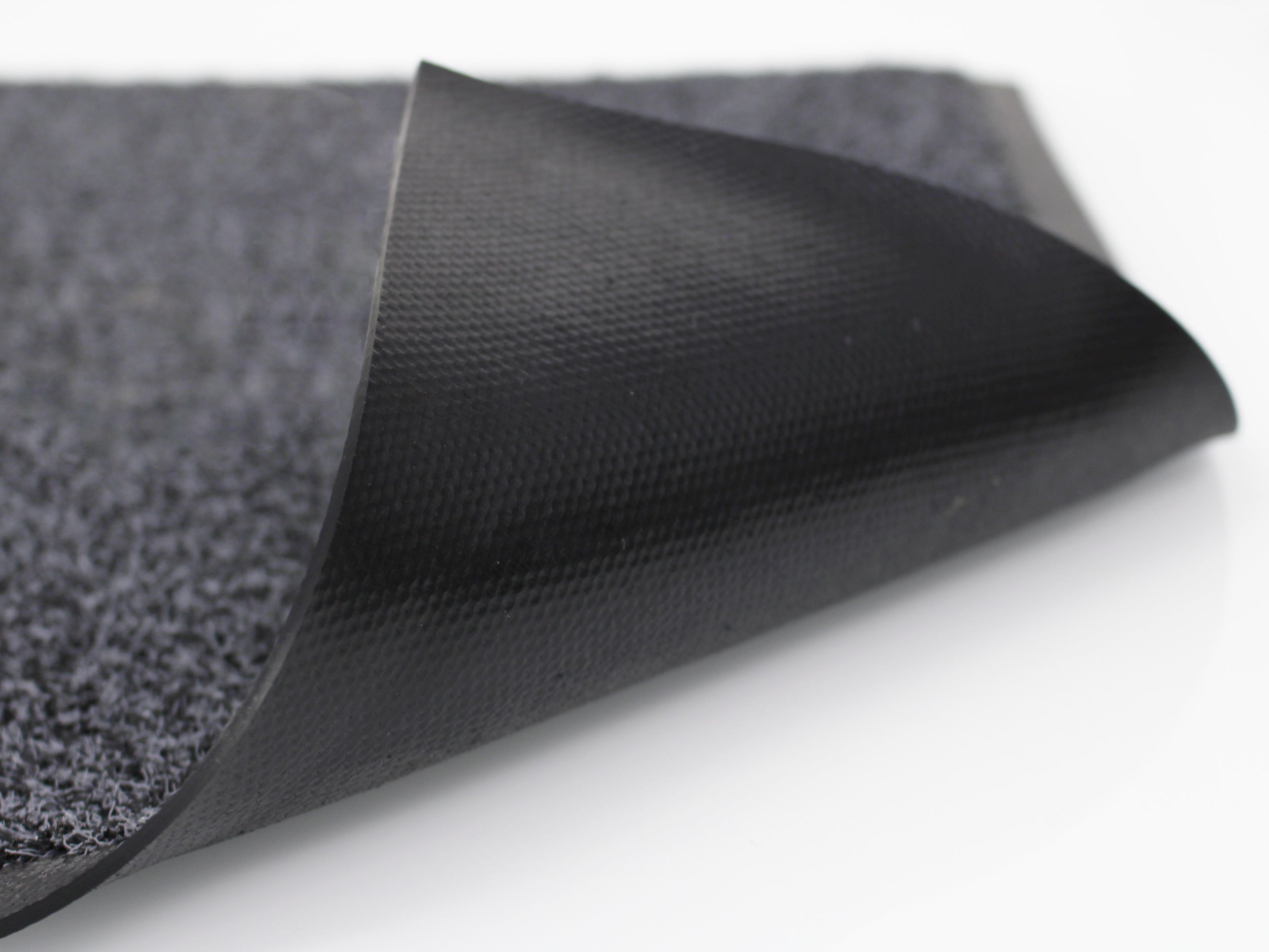 Schwarzes Gummi-Rückenmaterial einer umgeklappten Schmutzfangmatte für den Outdoorbereich