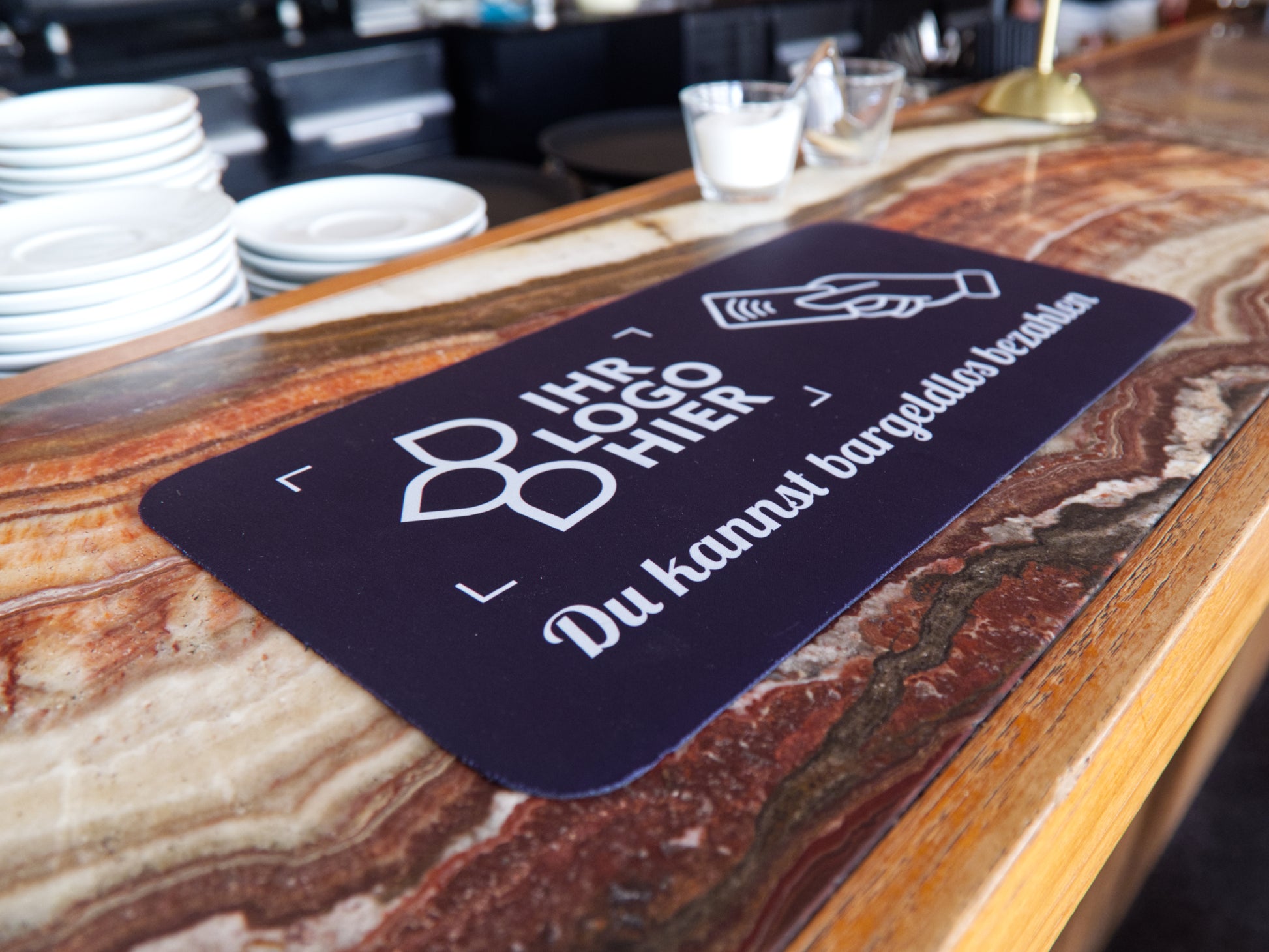 Thekenmatte mit mit Motiv "du kannst bargeldlos zahlen" liegt auf dem Tresen eines Cafés