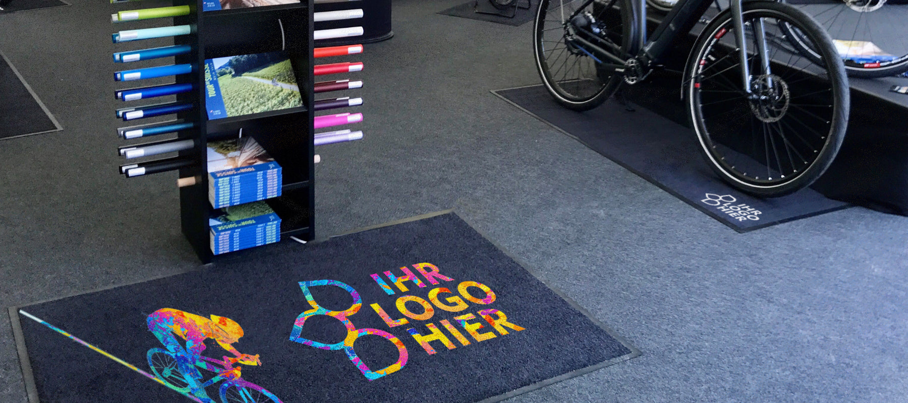 Bedruckte Fußmatte mit buntem Radfahrer Logo auf einer Fahrradmesse